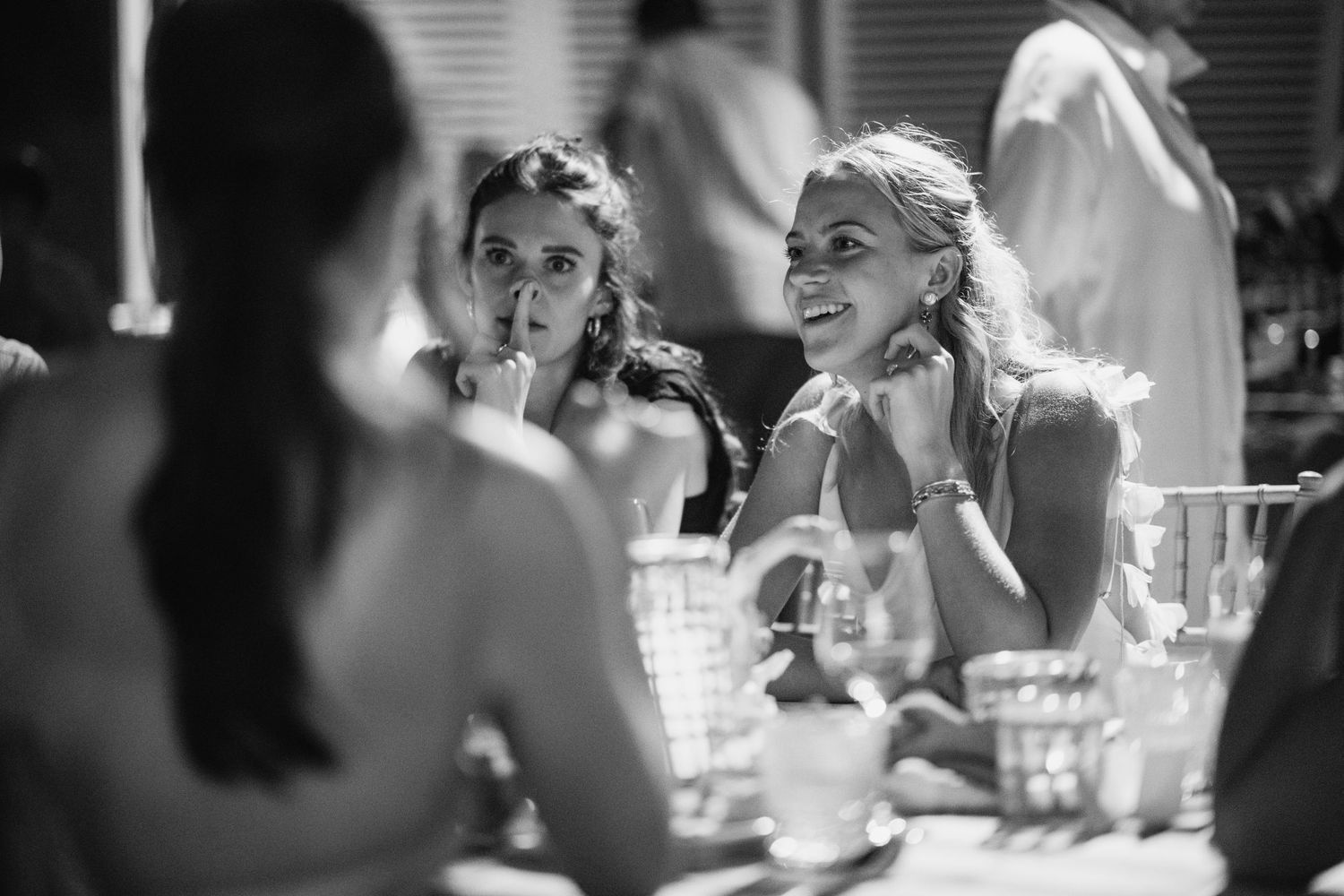Guests engaged in animated conversation at an elegant wedding reception with wine glasses.