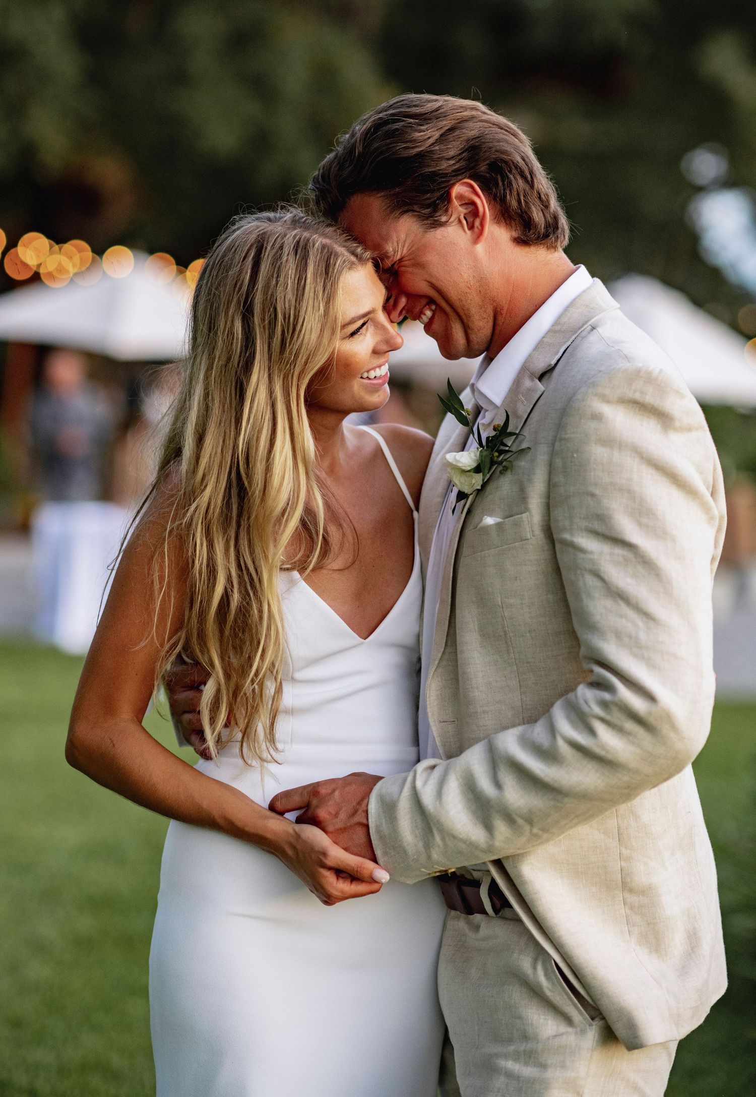 A romantic wedding couple embraces outdoors in a series of candid moments wearing white and beige attire.