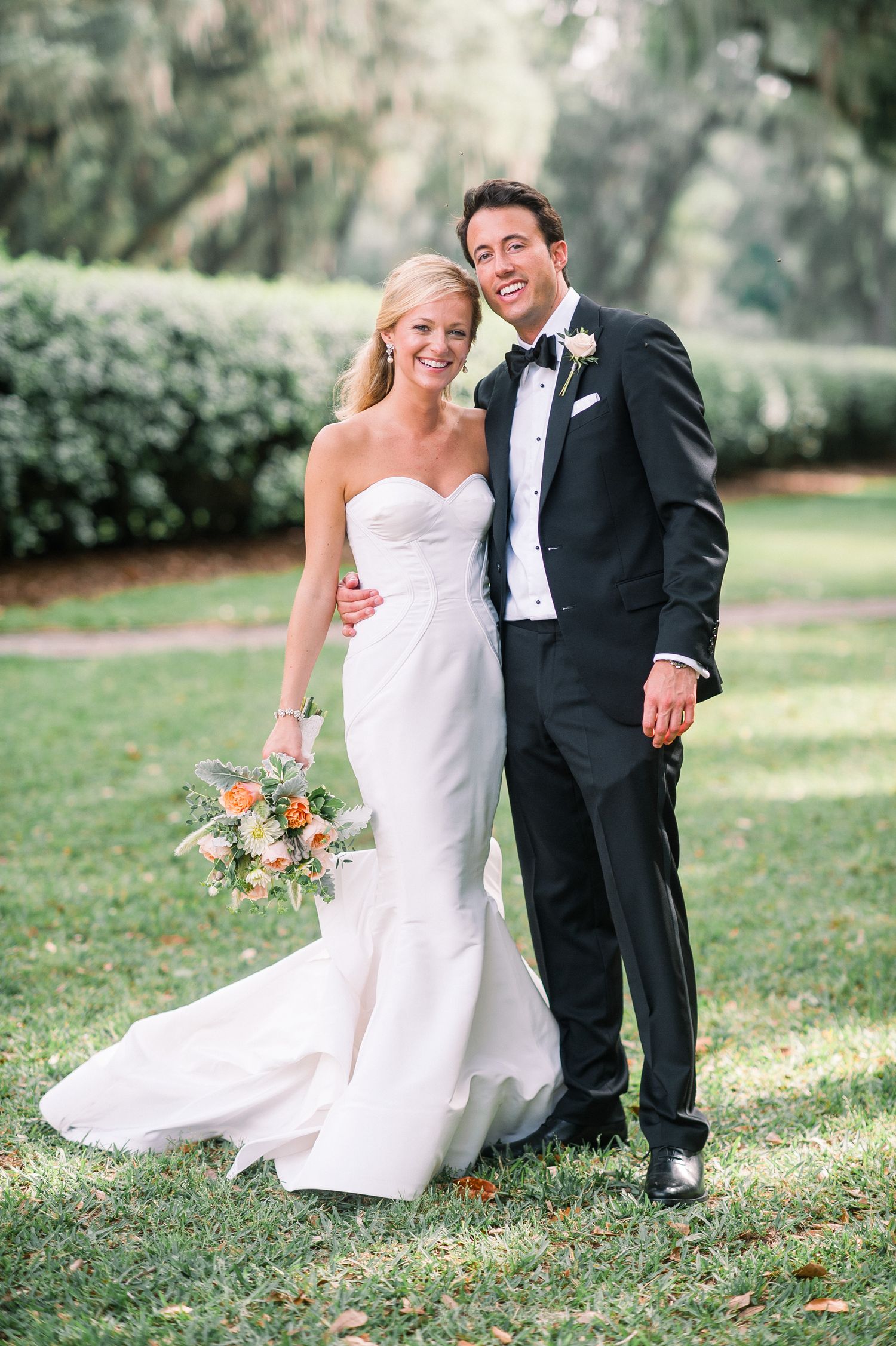 Newlyweds share playful moments on the grass during an outdoor wedding photo session.