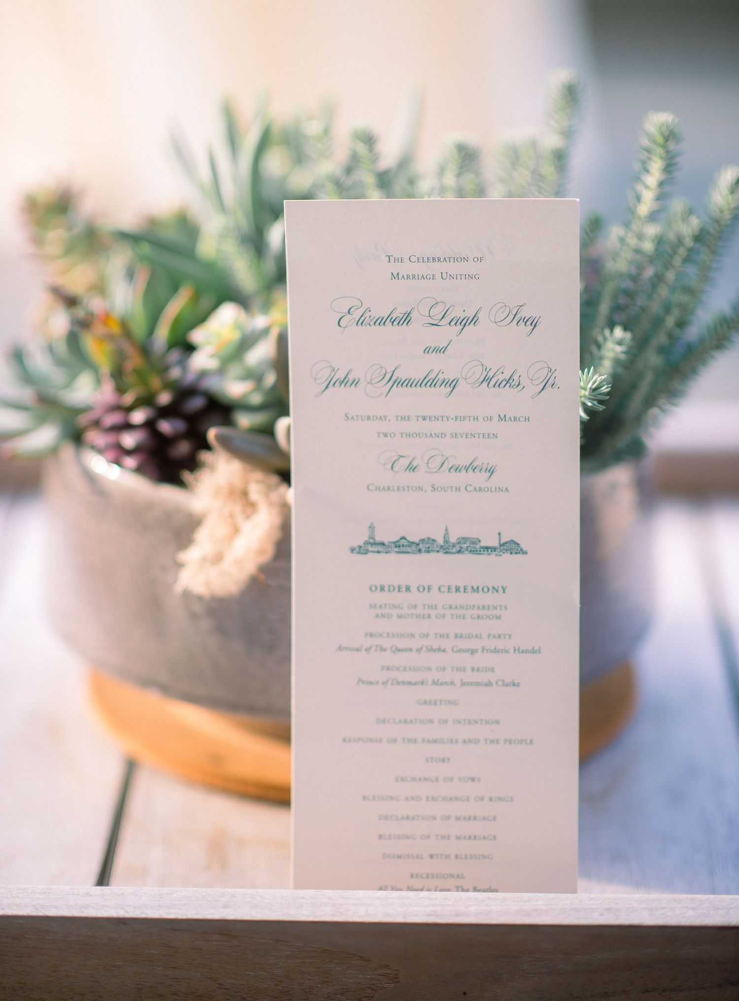 Elegant wedding invitation suite with blue text and floral decor elements displayed on a light background.