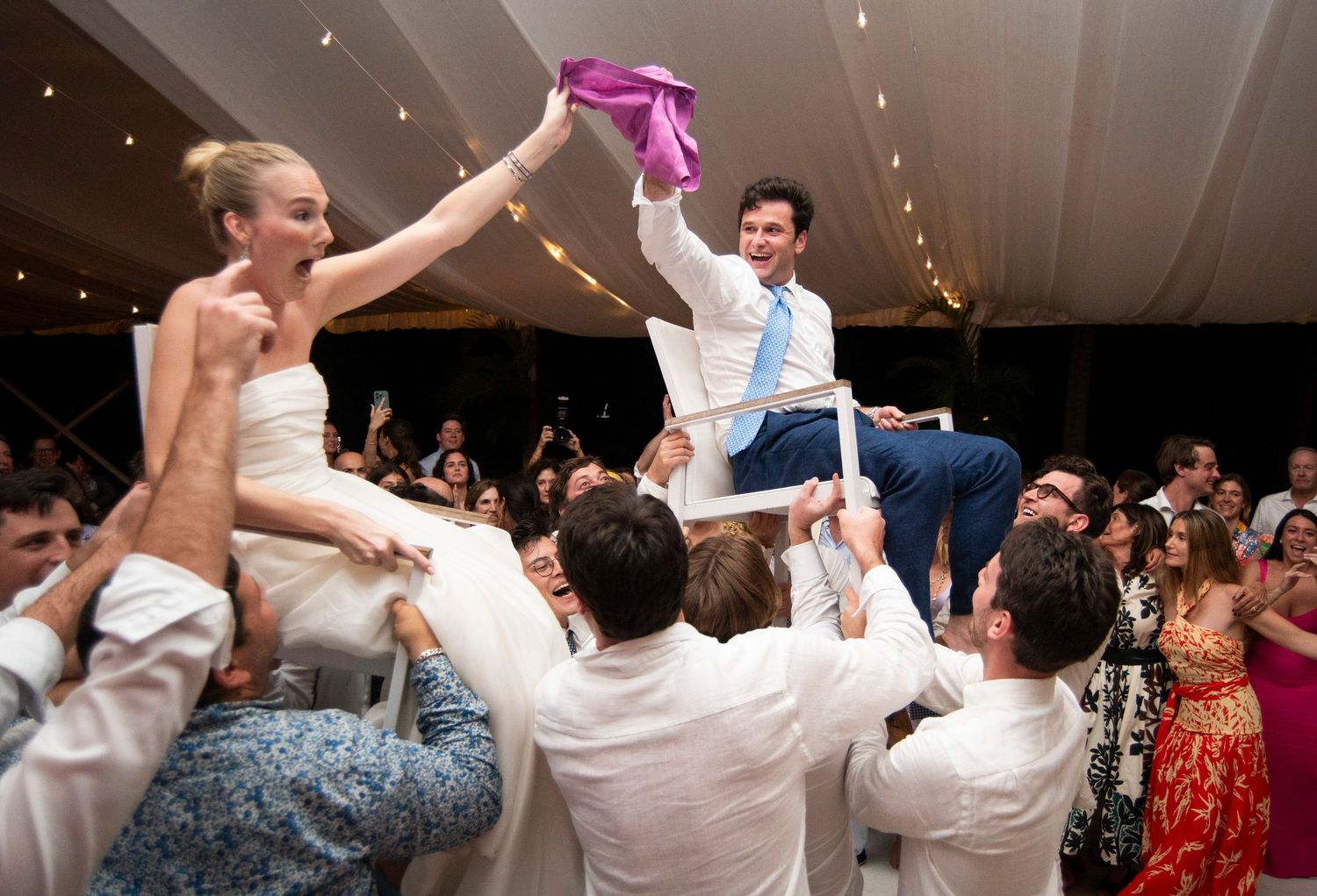 Wedding reception dance party with guests celebrating under indoor lighting.