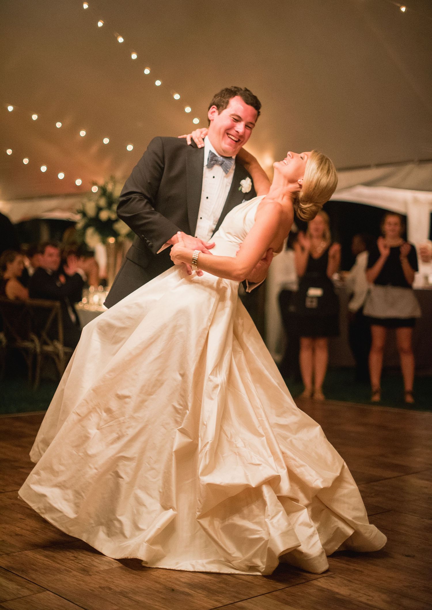A romantic first dance sequence at a wedding reception under twinkling lights with a bride in a flowing white gown.
