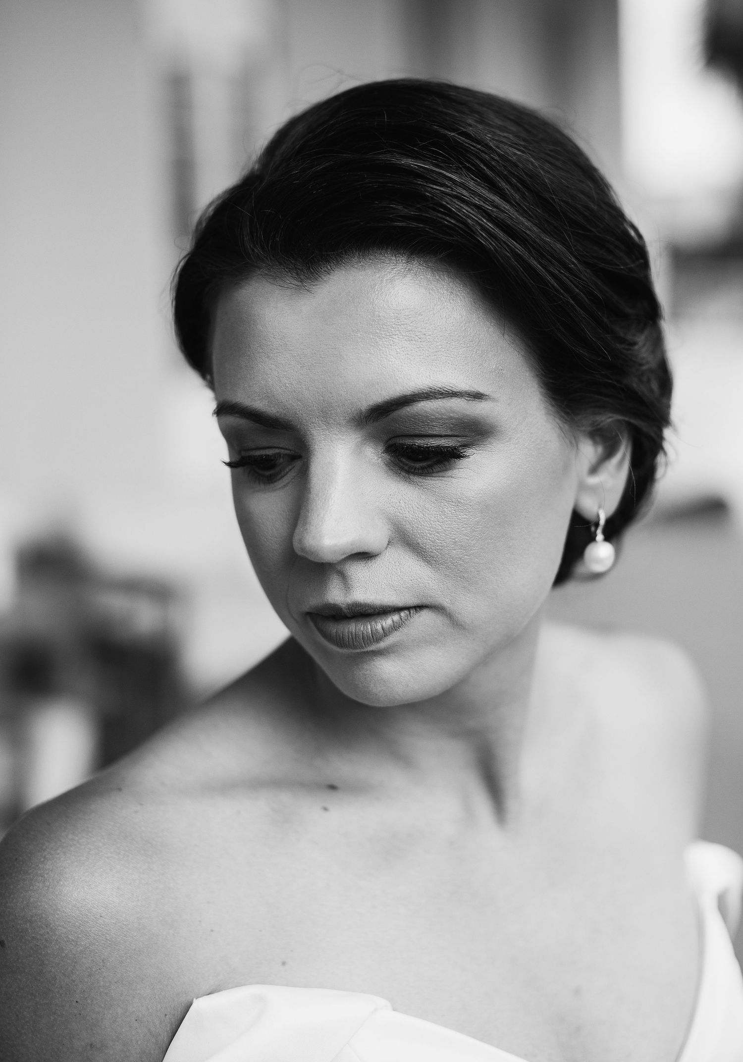A series of black and white portrait photographs showing a woman in a white dress looking down with a gentle smile.