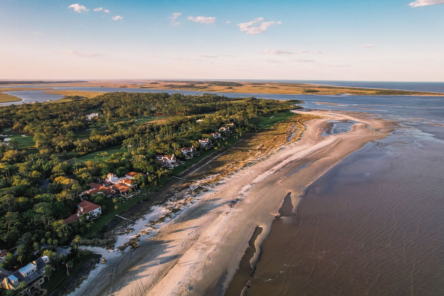 Aerial panoramic view of a scenic coastal landscape with sandy beaches, blue waters, and lush vegetation.