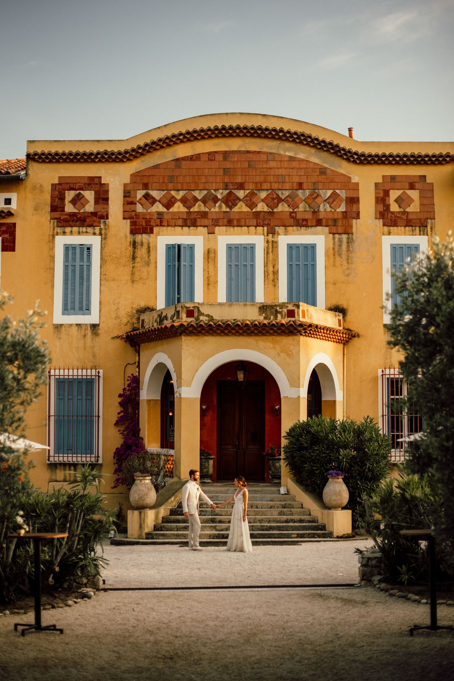 Mediterranean villa with yellow stucco walls, arched doorways, and ornate architectural details against an overcast sky.