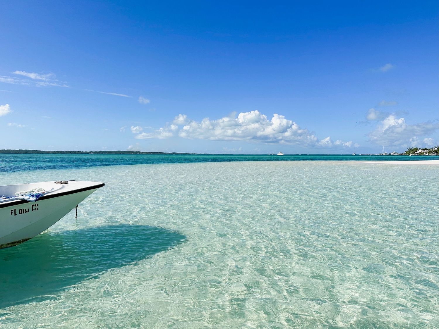 Crystal clear turquoise waters of a tropical lagoon with boats visible on the horizon.