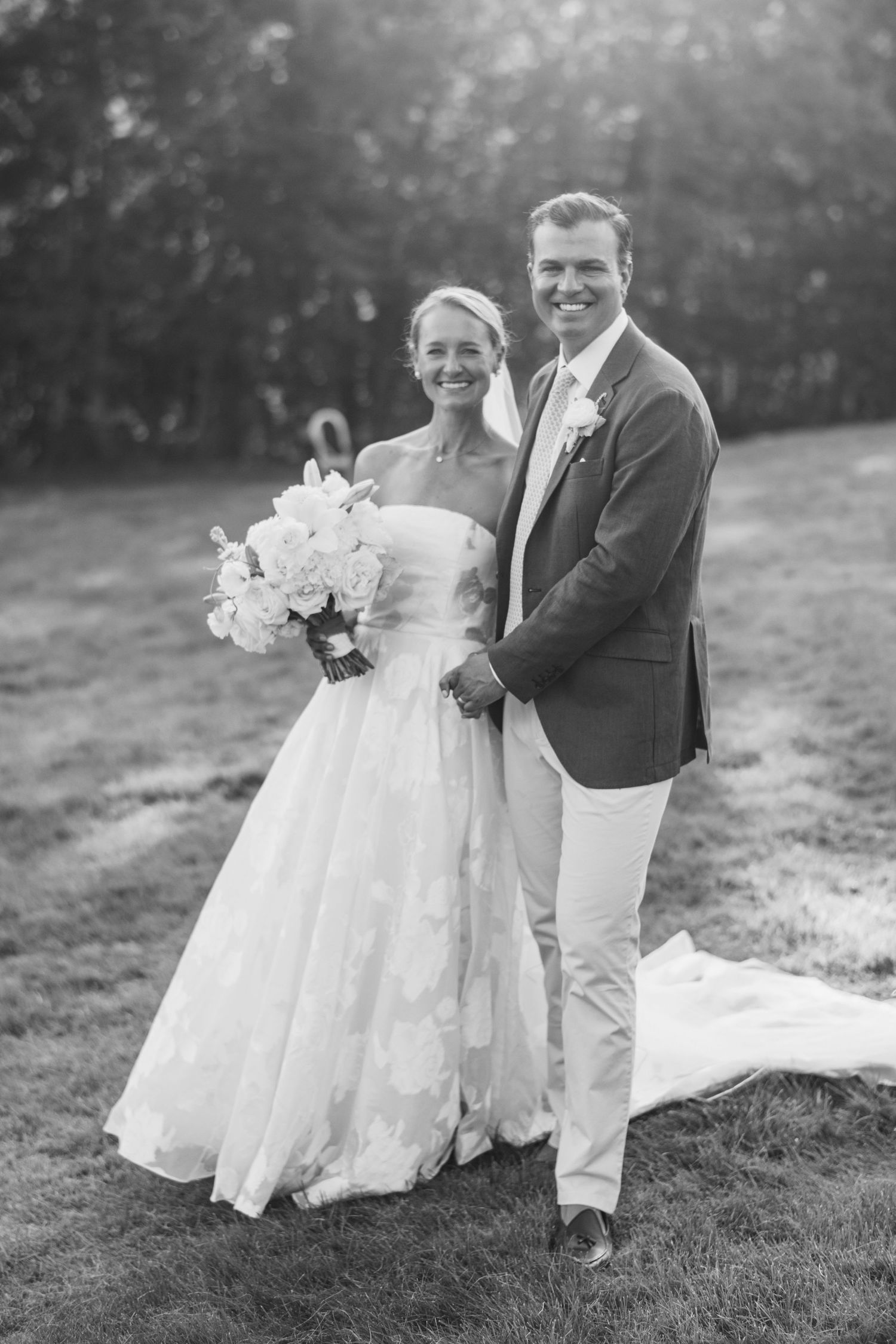 Black and white wedding portraits on grassy hillside with flowing dress.