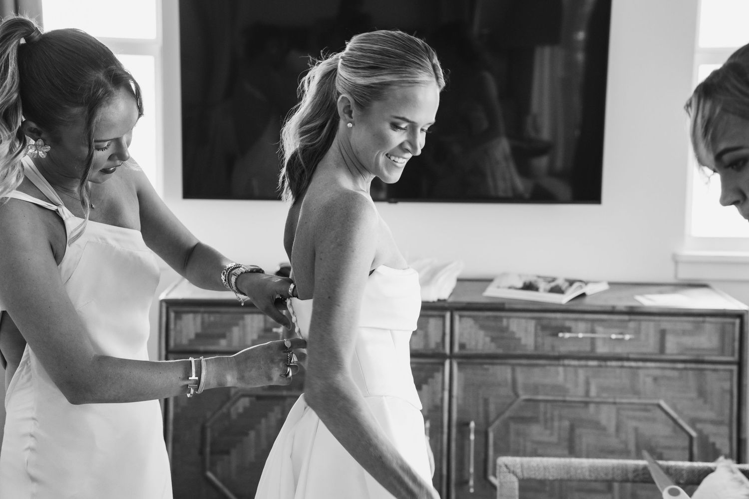 Black and white image of wedding dress preparations in a sunlit room.