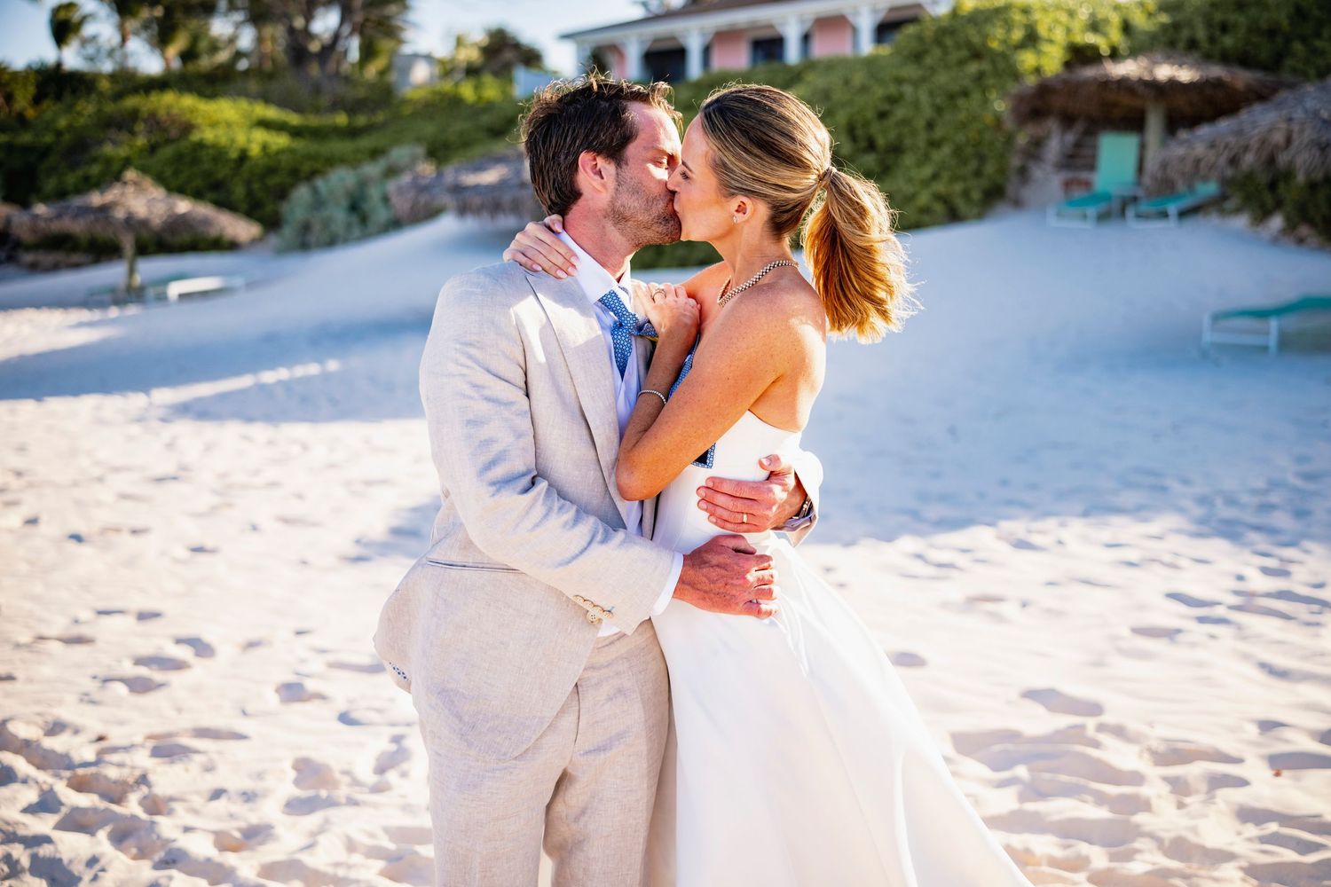 Romantic beach wedding portrait with couple embracing against ocean backdrop.