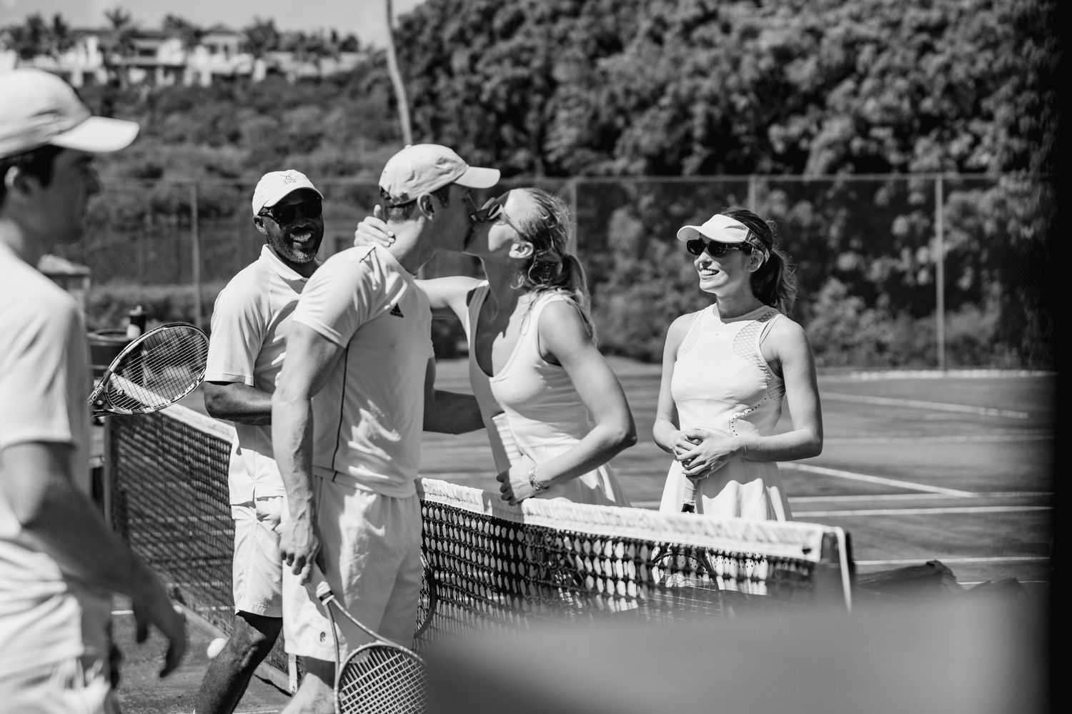 Black and white photo of tennis players practicing and training on outdoor courts during a sunny day.