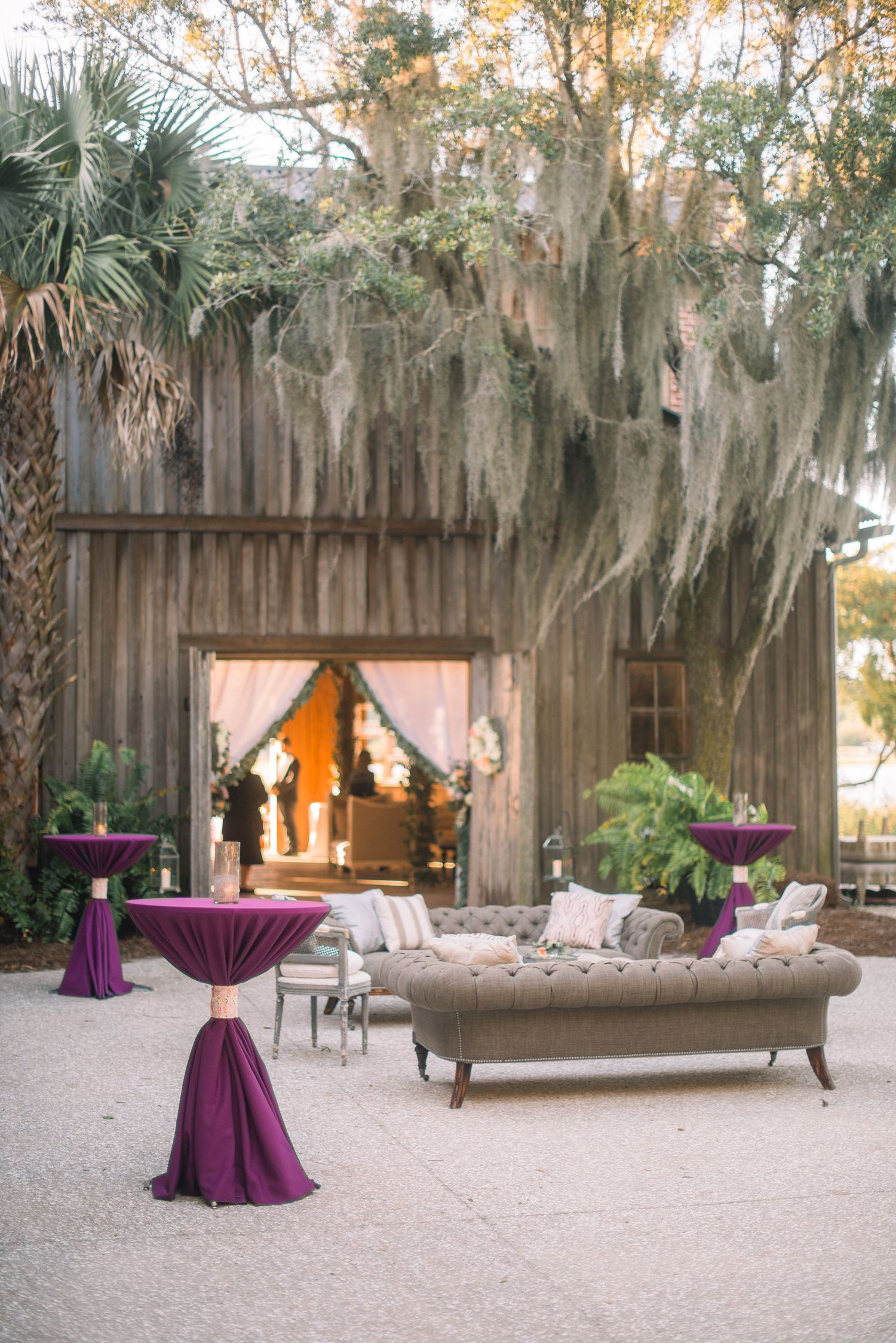 Outdoor wedding venue setup with rustic wooden backdrop and elegant purple draping in a natural garden setting.