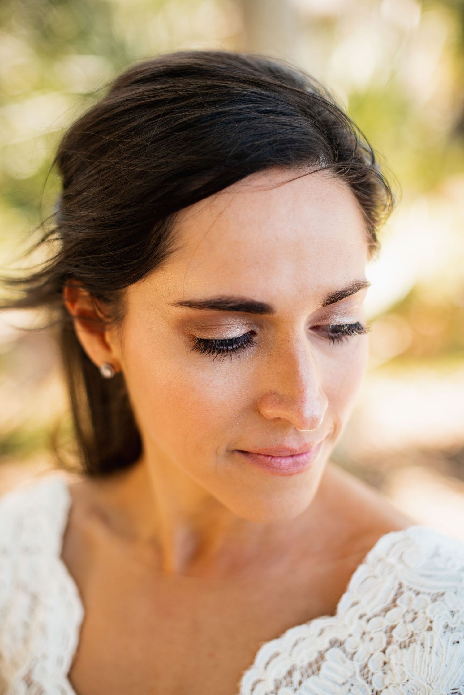 Close-up portrait of someone wearing white lace with soft natural lighting and downcast eyes.
