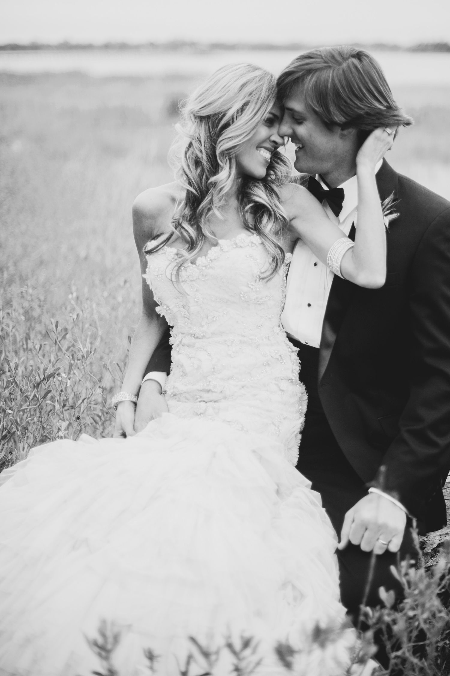 Romantic black and white wedding photo series showing tender moments between newlyweds in a field.