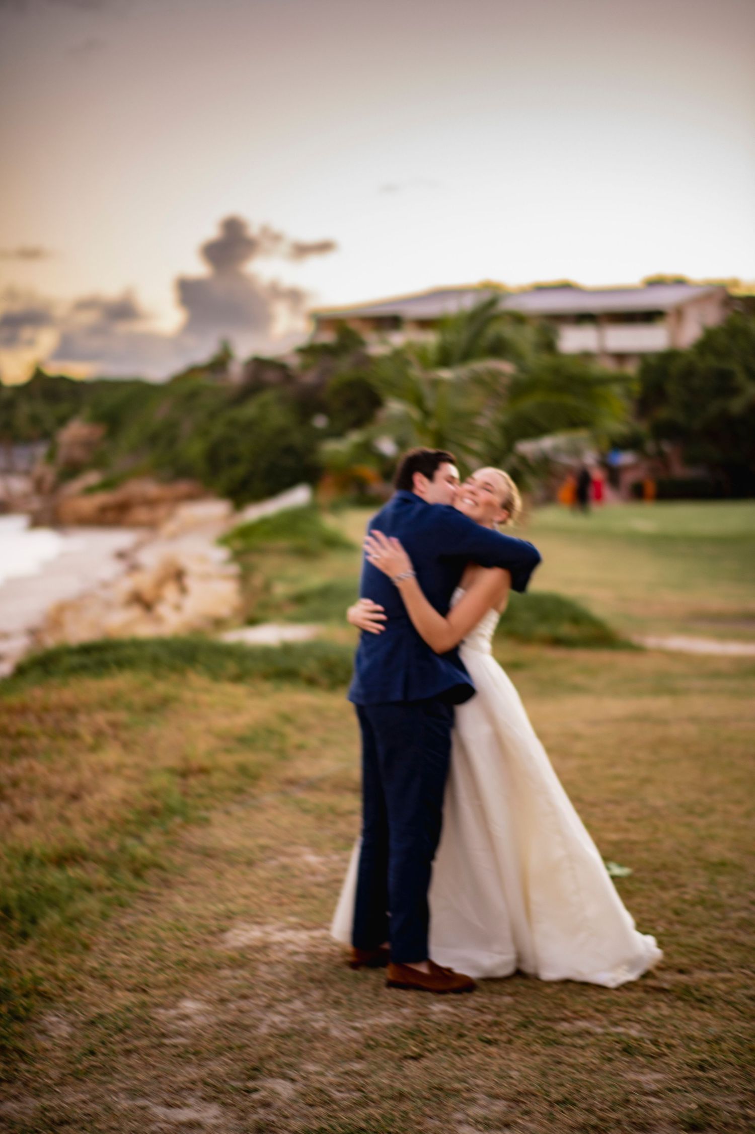 Romantic sunset wedding photos on a grassy hillside overlooking the ocean.