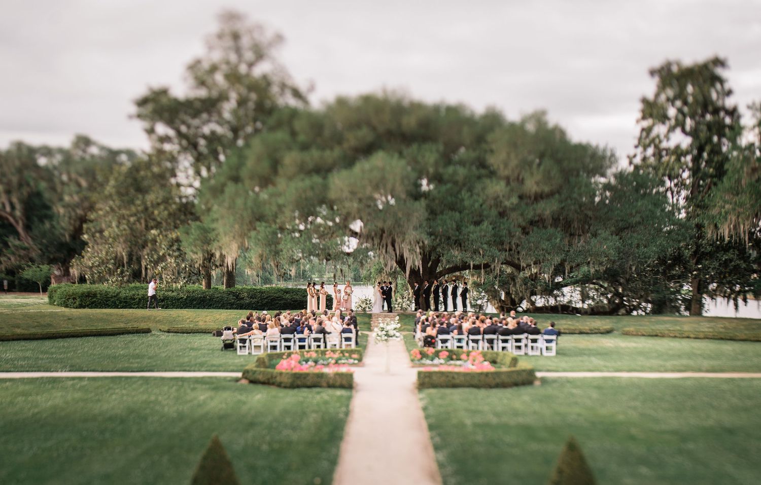A panoramic view of a formal garden pathway lined with trees and ornate flowerbeds stretches into the distance.