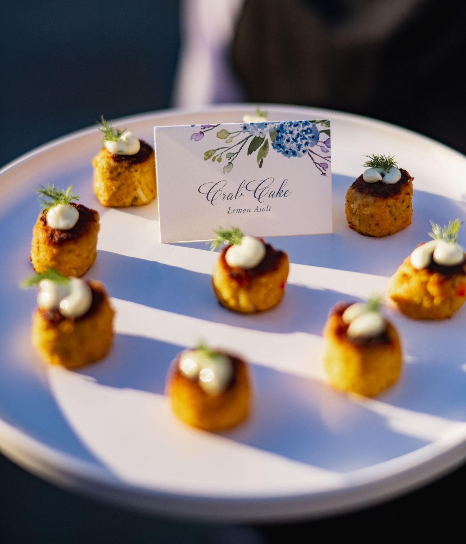 Elegant catering appetizers with caviar and cream served on small round crackers cast dramatic shadows on white plates.