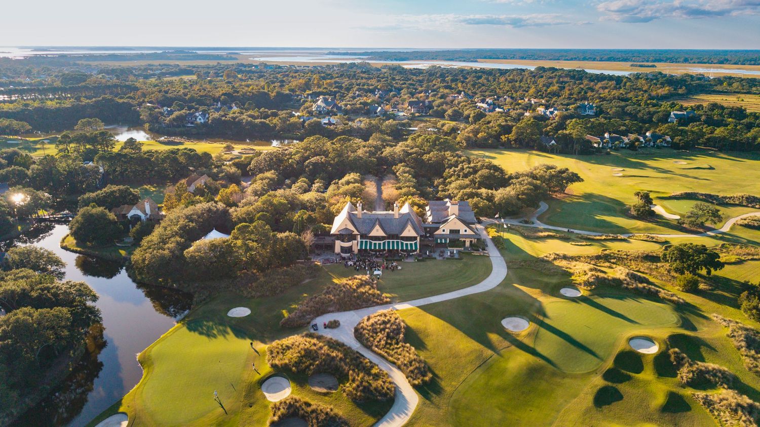 Aerial panoramic view of coastal town with residential neighborhoods and rolling green hills stretching to horizon.