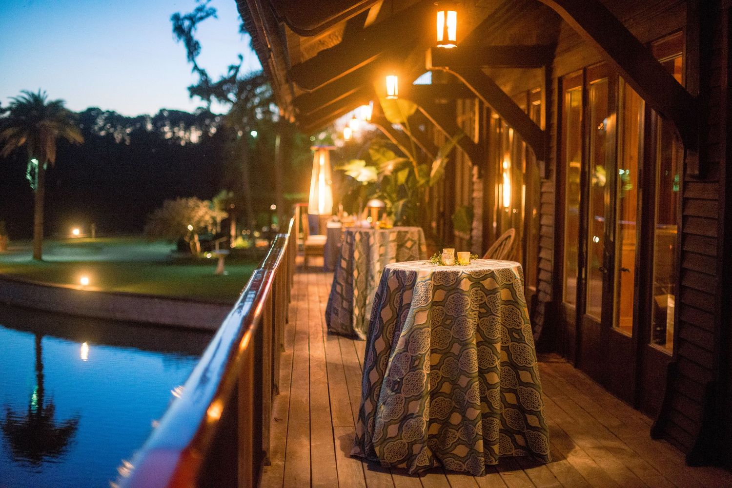 Evening poolside deck with illuminated cocktail tables and glowing lanterns at an elegant outdoor venue.