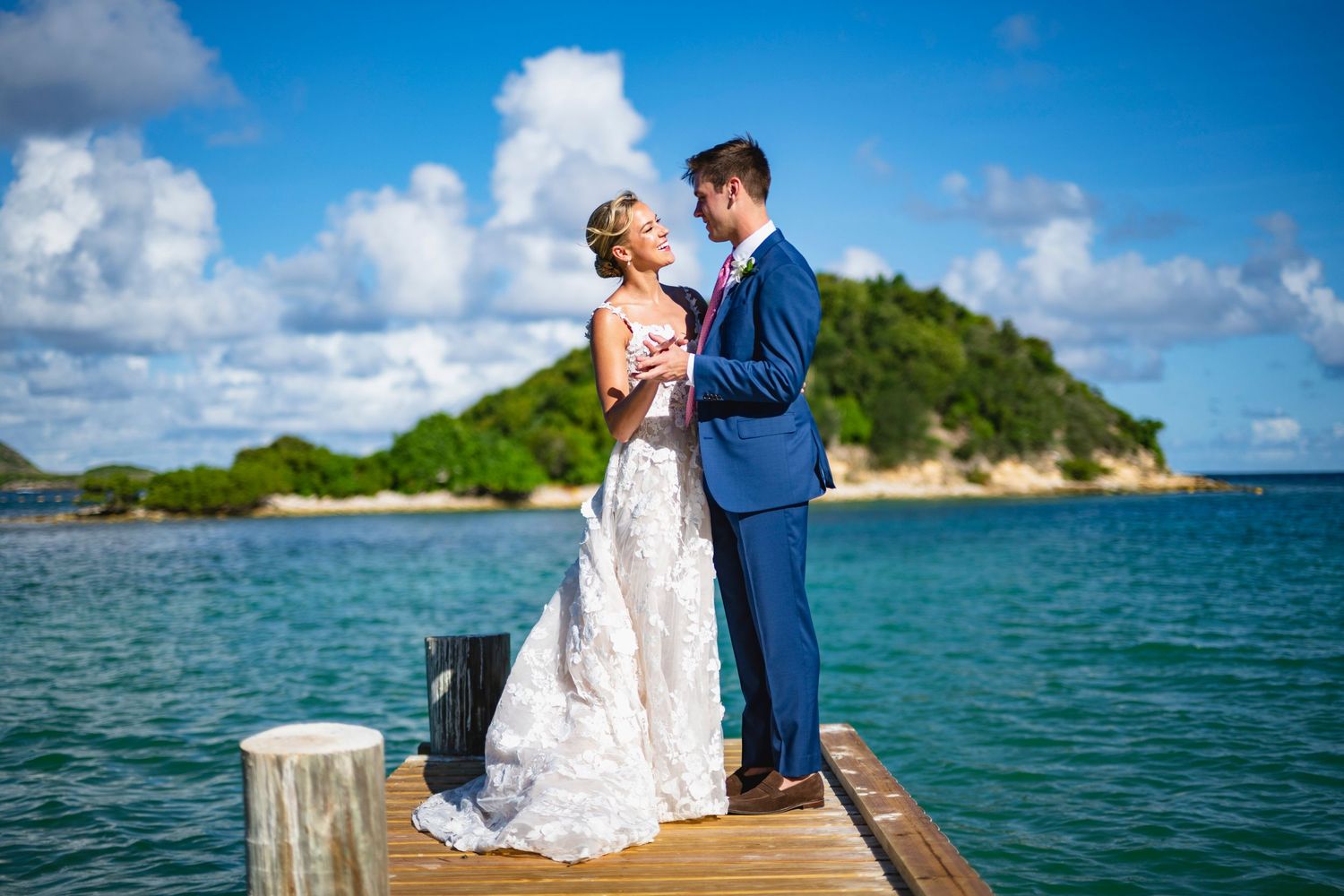 Scenic waterfront wedding photography session with turquoise waters and lush green islands in background.