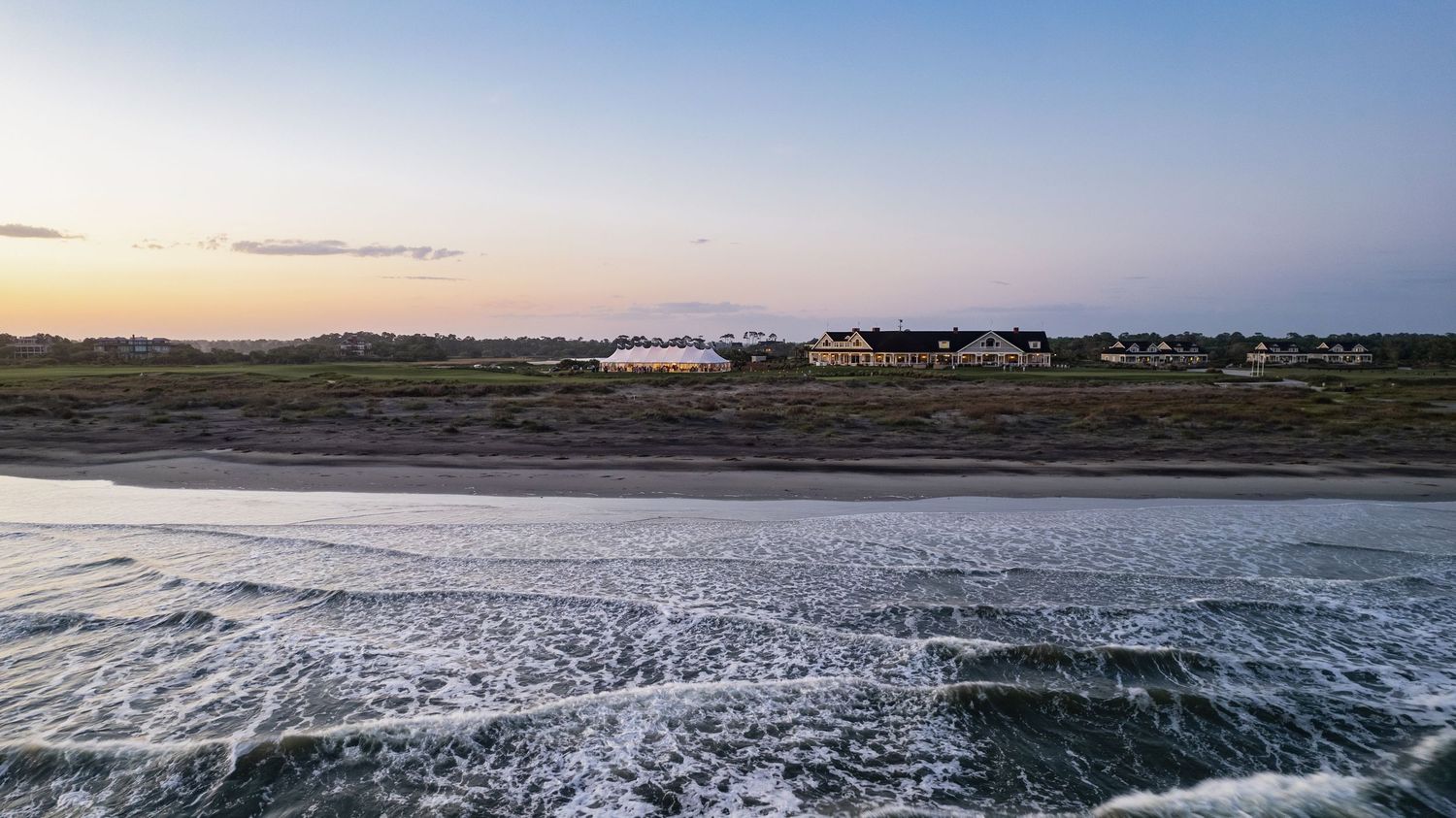 Sunset view over a frozen coastline with buildings visible in the distance on the horizon.