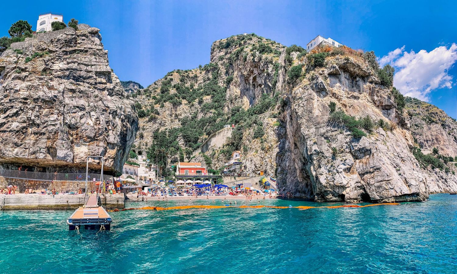 Dramatic coastal cliffs with beach cove and crystal blue Mediterranean waters near seaside village of Amalfi coast