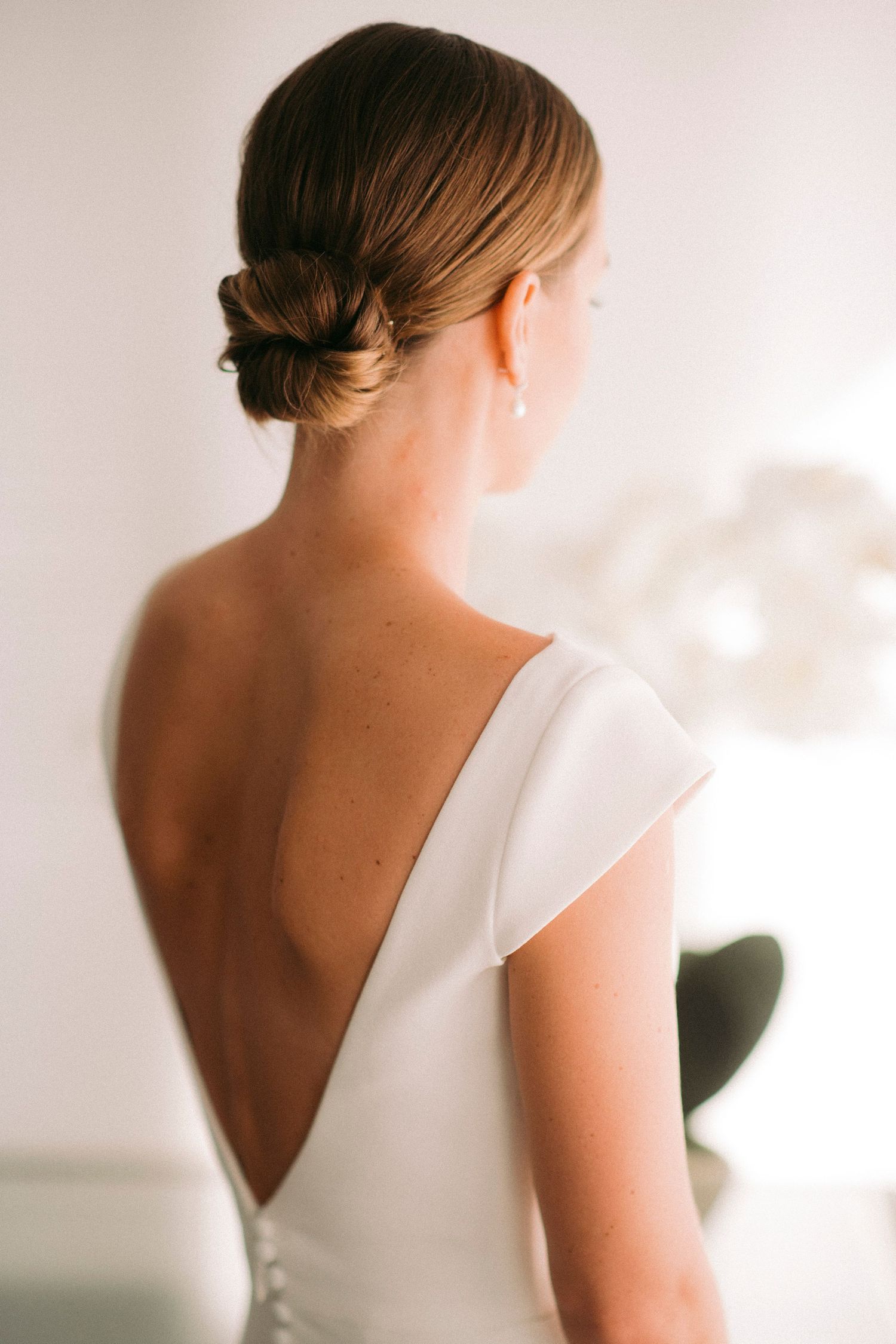 A series of elegant bridal portraits showing the back details of a classic white wedding dress.