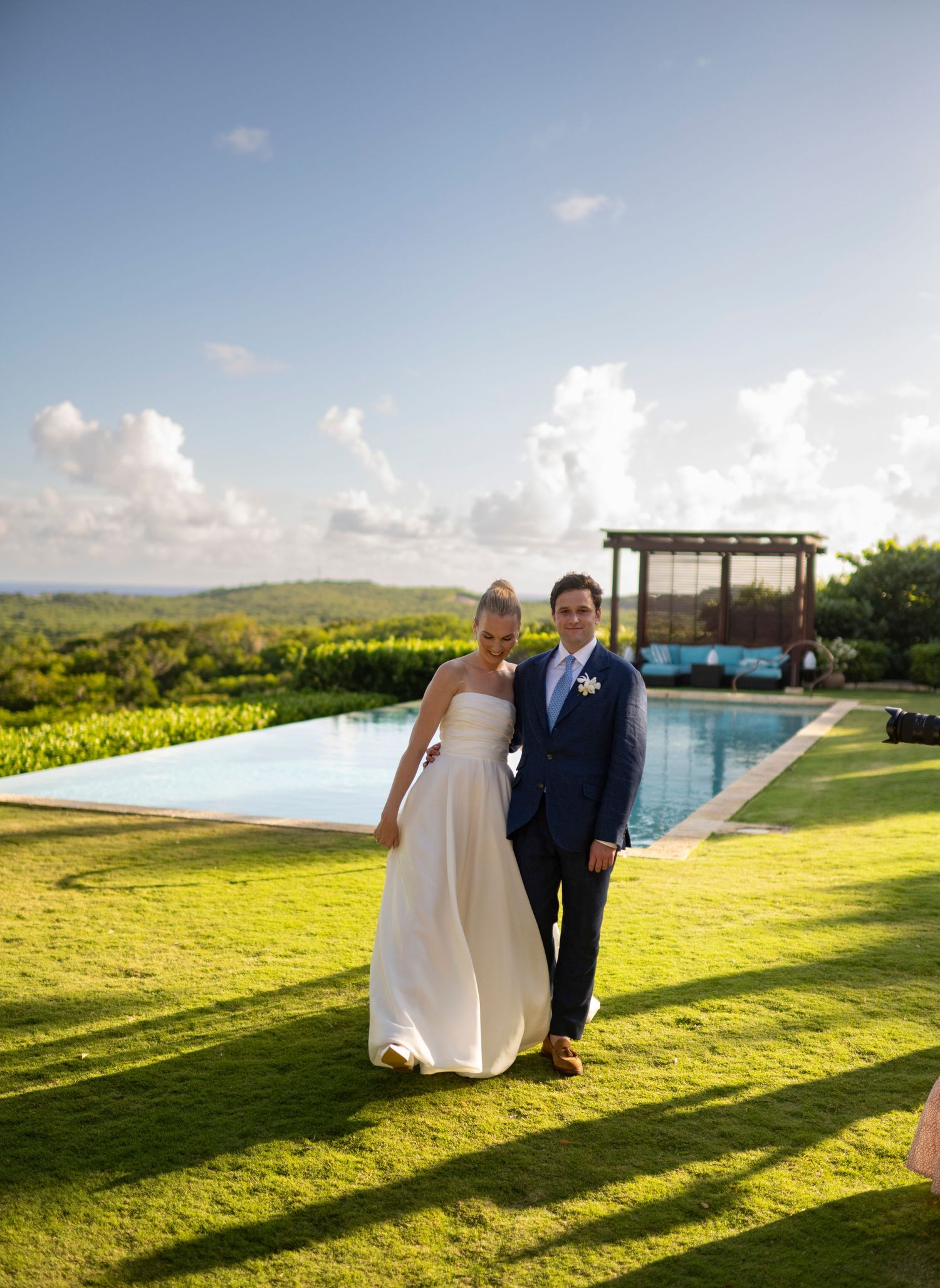Wedding couple photographed at sunset by an infinity pool with mountain views.