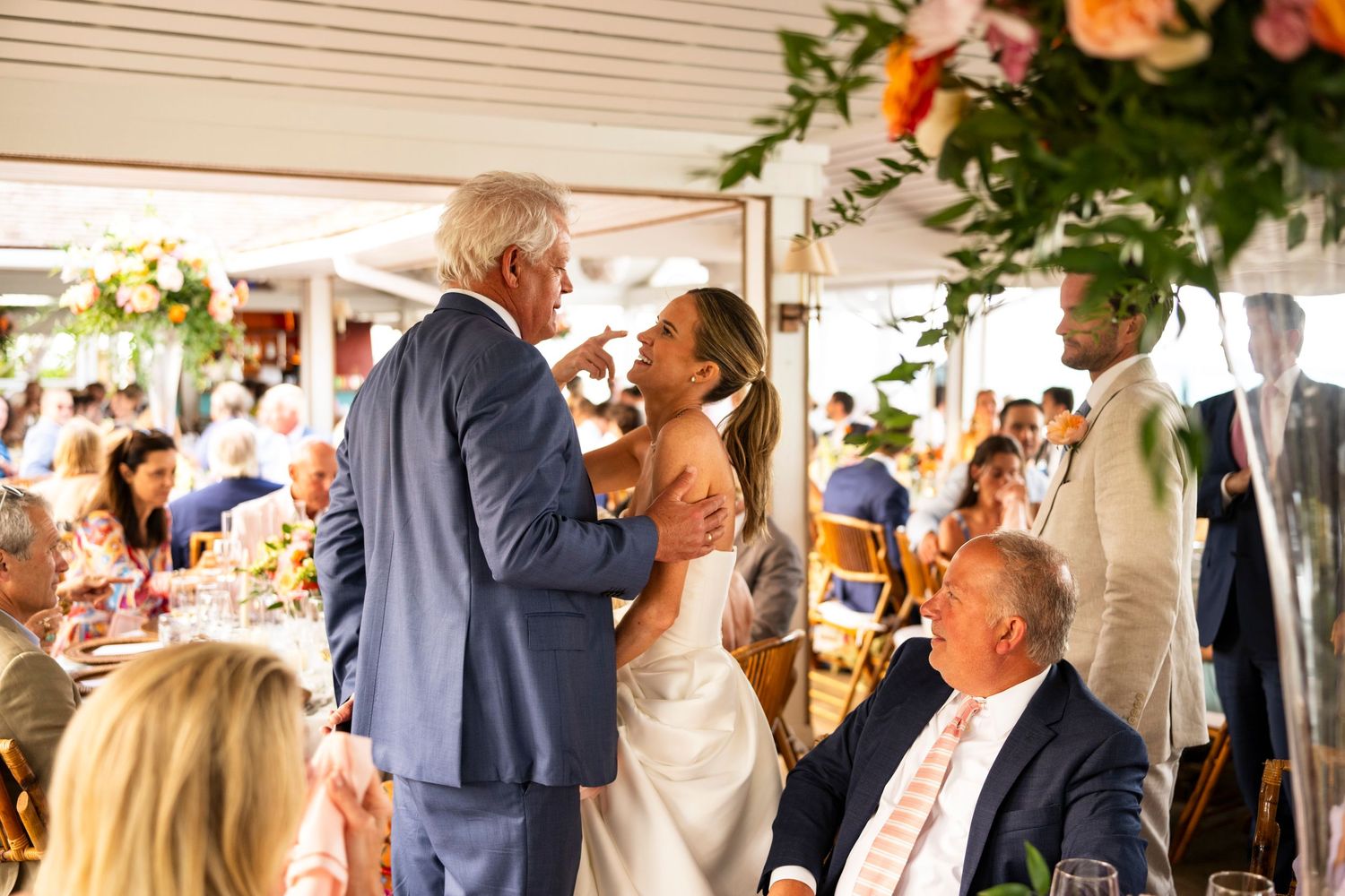 Reception celebration with floral decorations and guests gathered around decorated tables.