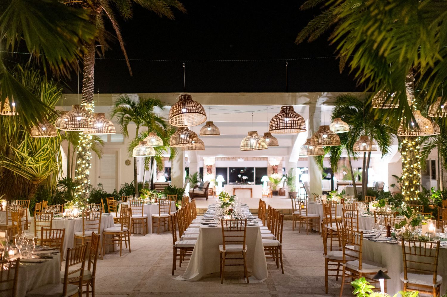 Elegant wedding reception setup with palm trees and ambient lighting.