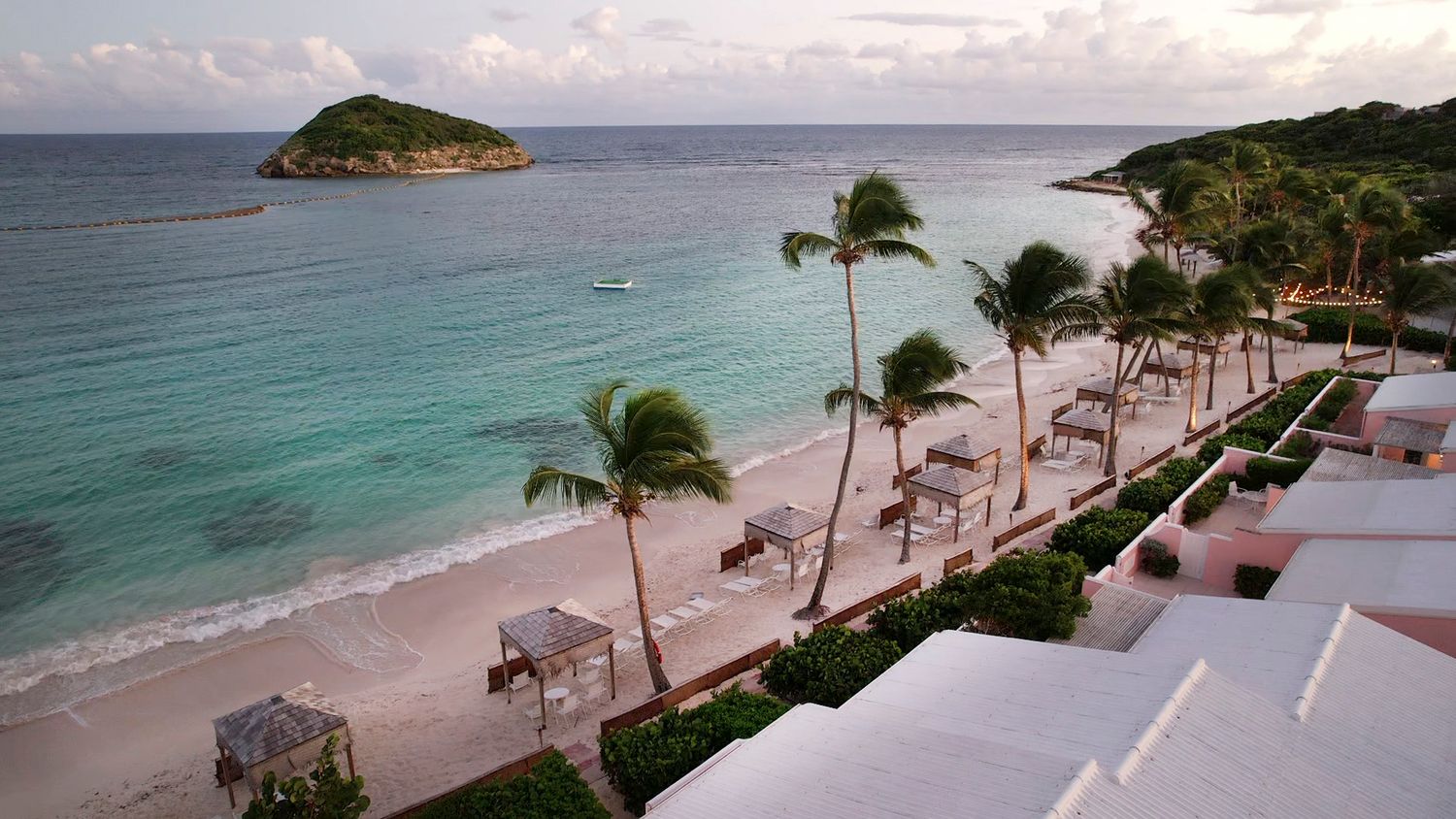 Panoramic view of a pristine beach resort with palm trees and turquoise ocean waters.