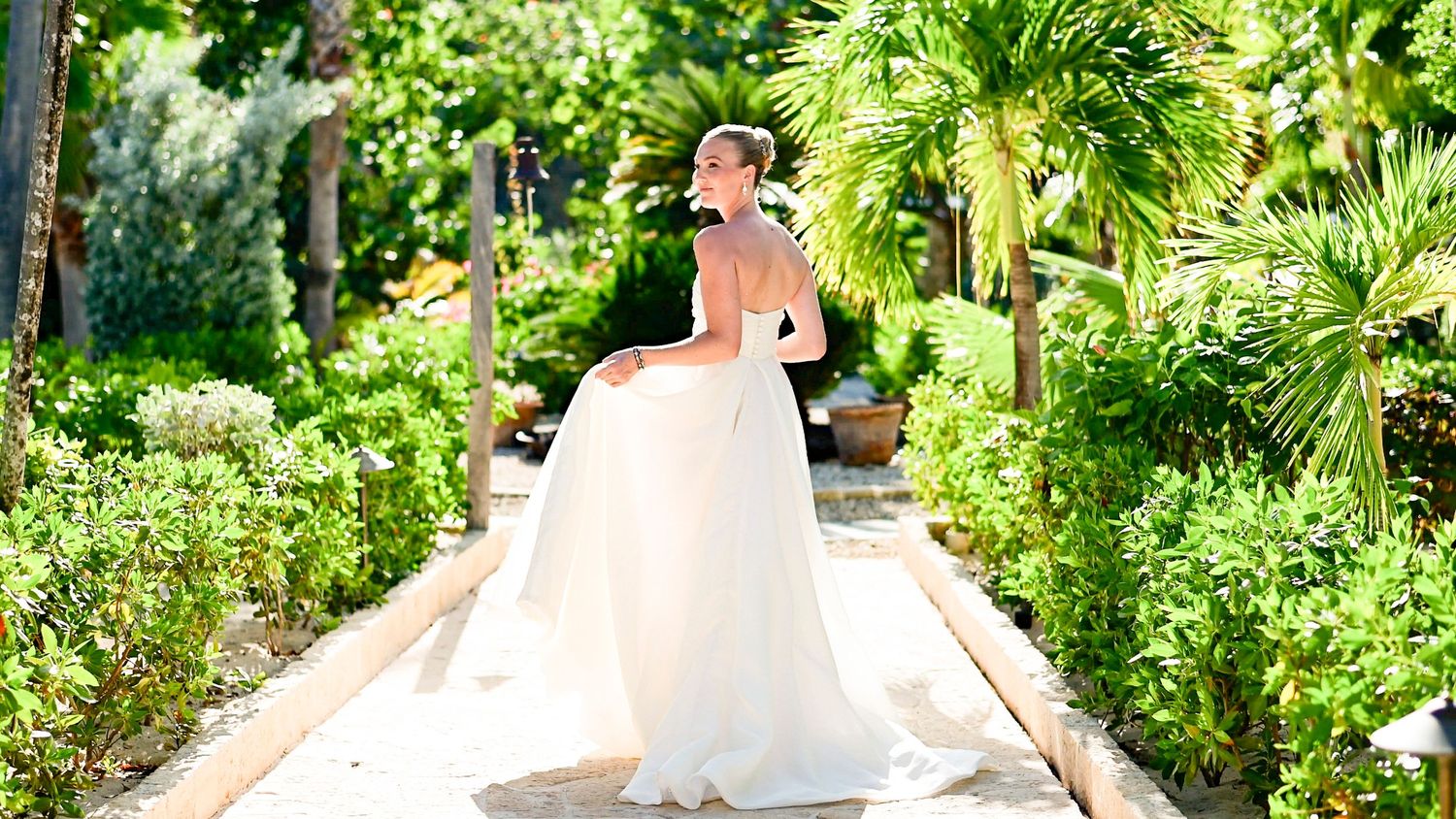 Lush tropical garden pathway with palm trees and vibrant greenery creating a natural archway.