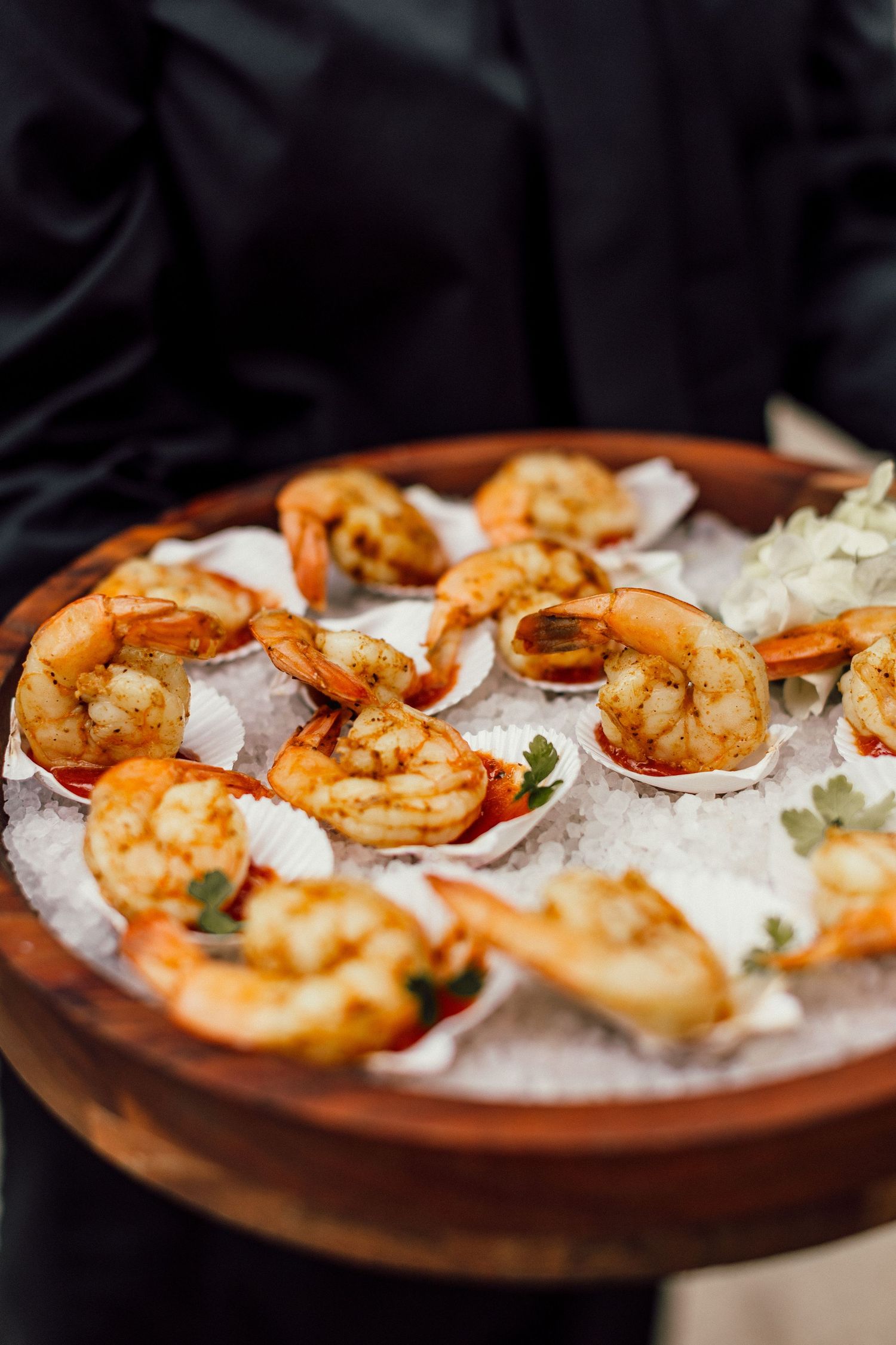 Grilled jumbo shrimp served on a rustic wooden platter with crushed ice and garnish in dramatic lighting.