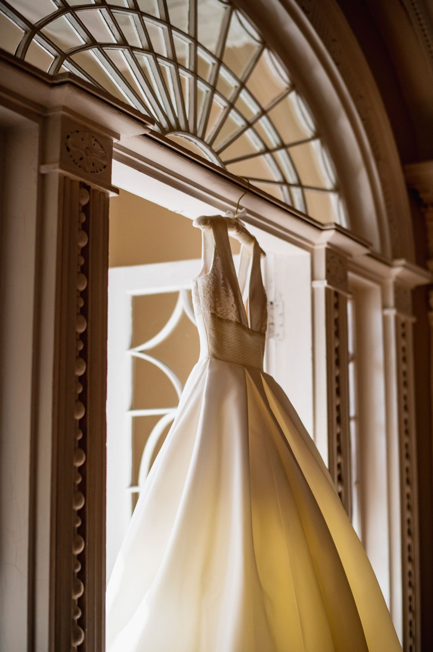 Architectural detail showing curved window arches with elegant white curtains creating a repeating pattern in warm sunlight.