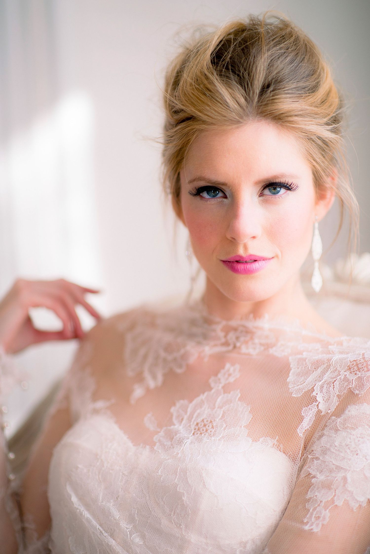 Elegant bridal portrait featuring delicate lace details, pearl earrings, and soft romantic makeup in natural lighting.