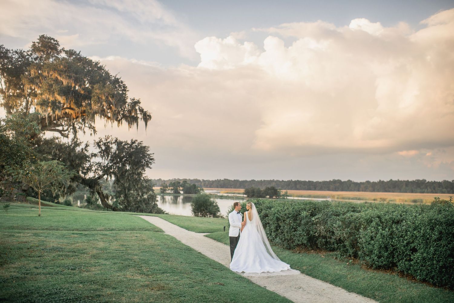 Scenic wedding ceremony photos at sunset overlooking a serene lake with lush greenery and golden hour lighting.