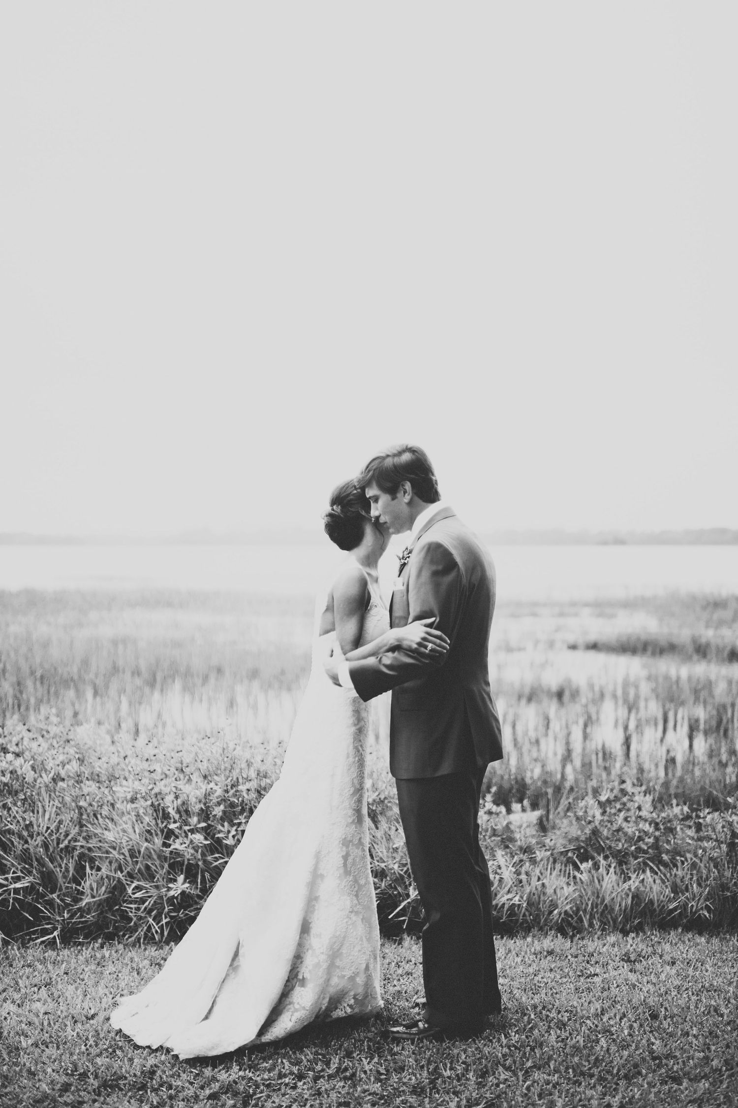 Romantic black and white wedding photos showing couple embracing in a scenic outdoor field.