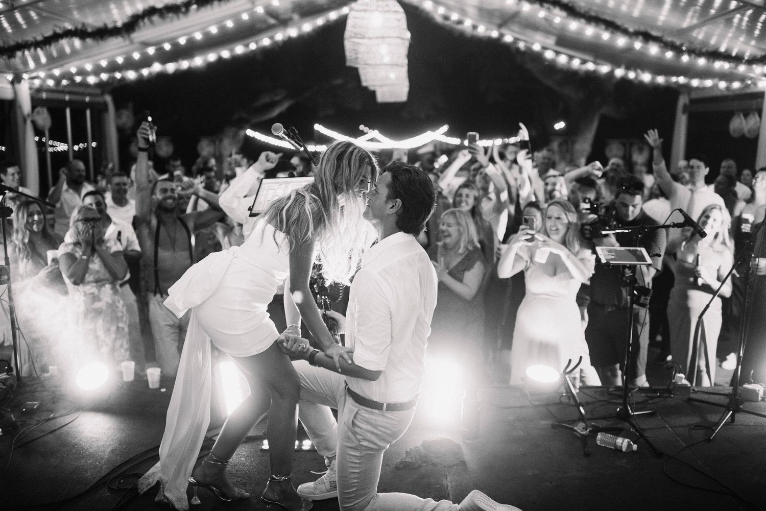 People dancing under string lights and paper lanterns at an outdoor evening celebration.