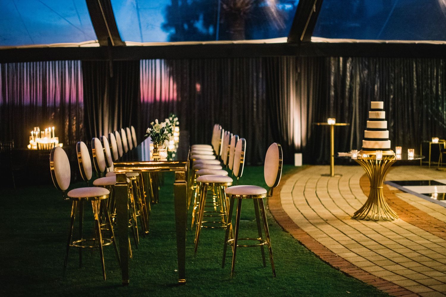 A panoramic view of an elegant wedding reception venue with gold chairs and ambient lighting creating a romantic atmosphere.