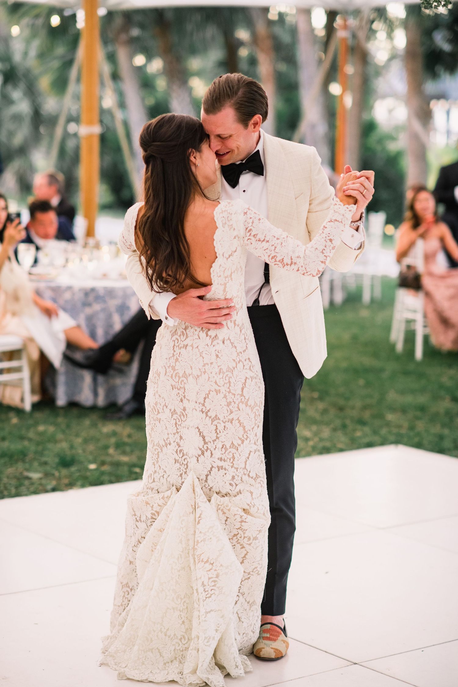 Couple shares romantic first dance on outdoor dance floor at elegant garden wedding reception.