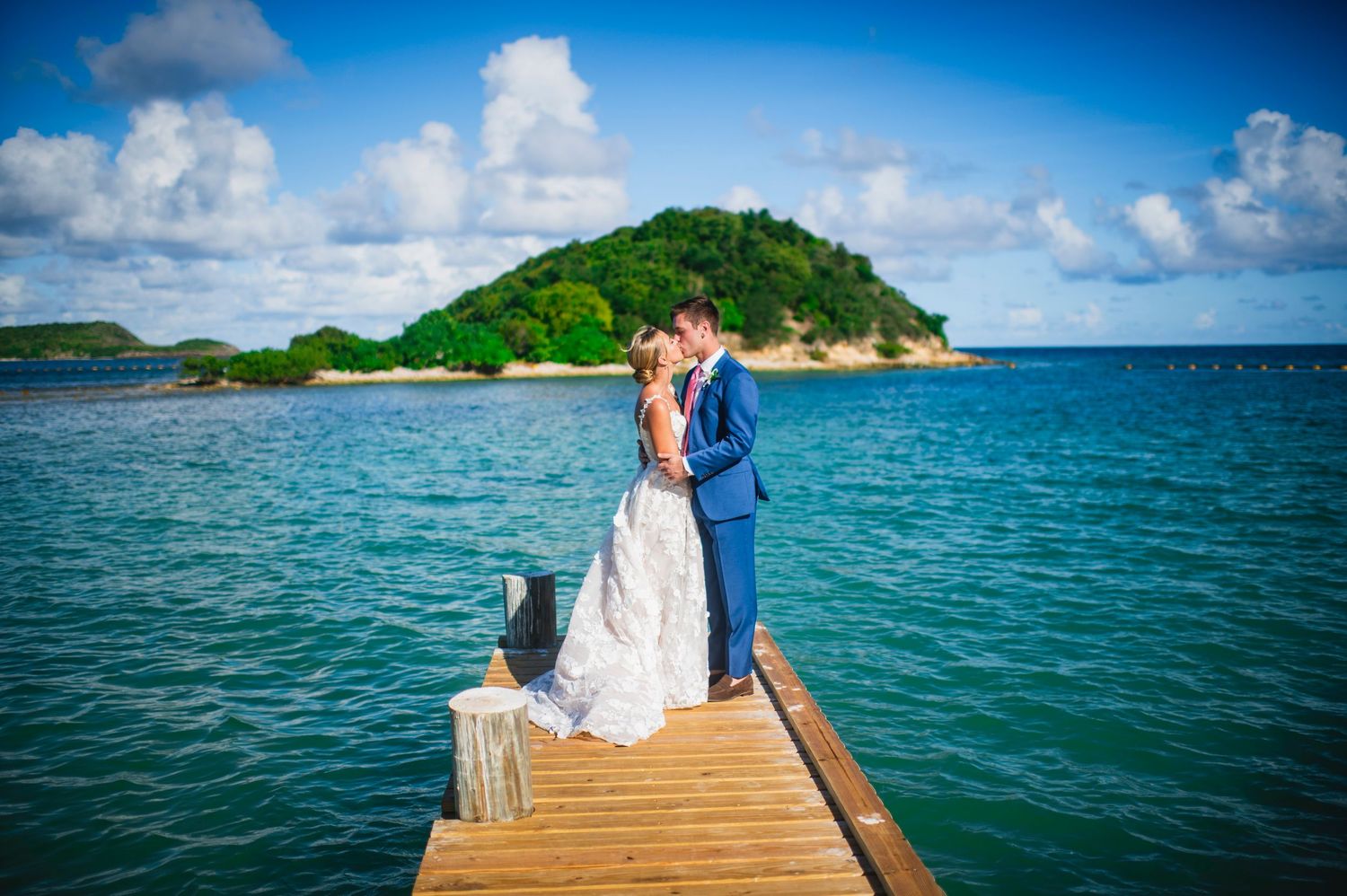 Wooden dock extending into turquoise waters with tropical islands in the background.