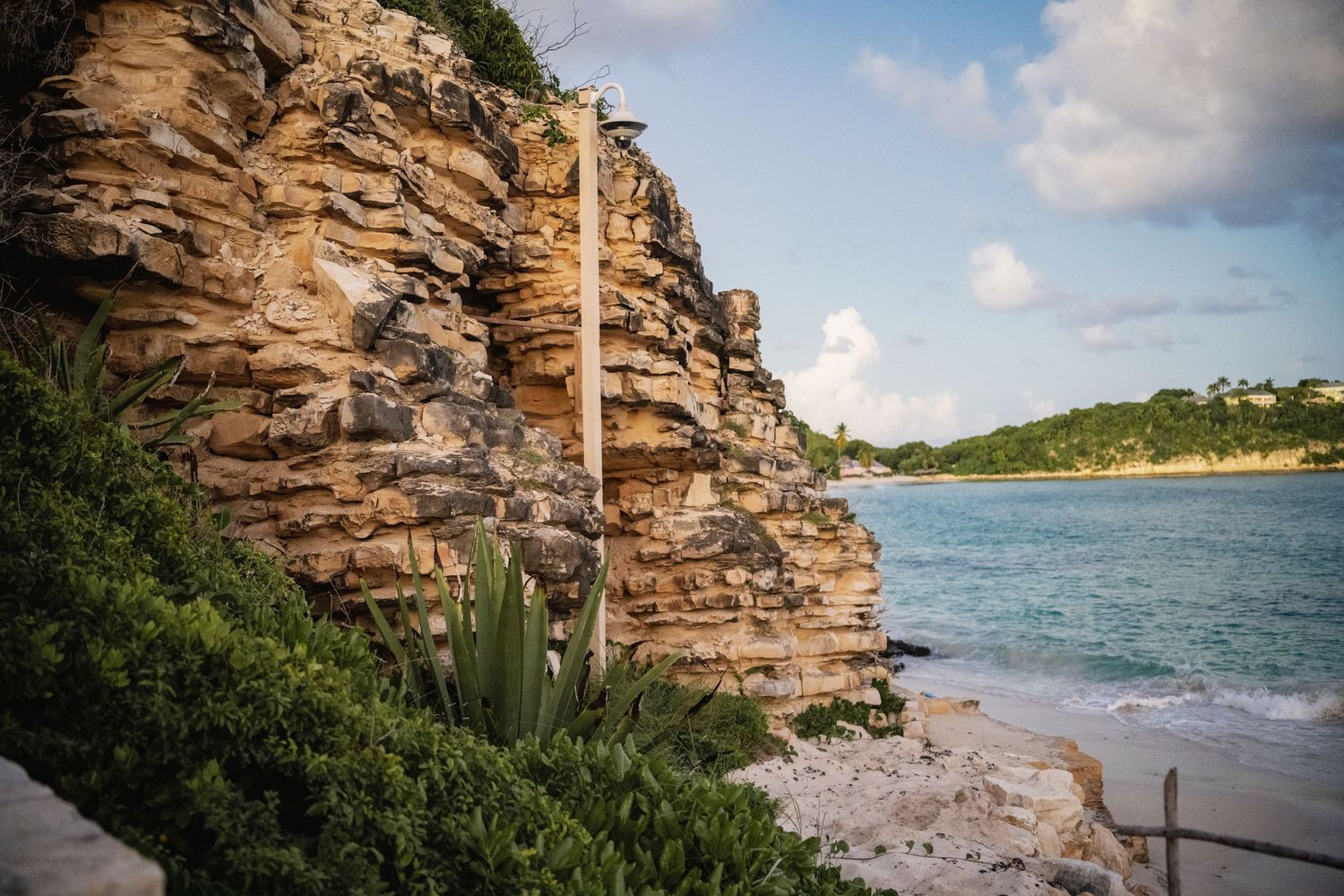 Rocky coastal cliffs and beach landscape with ocean views under blue skies.