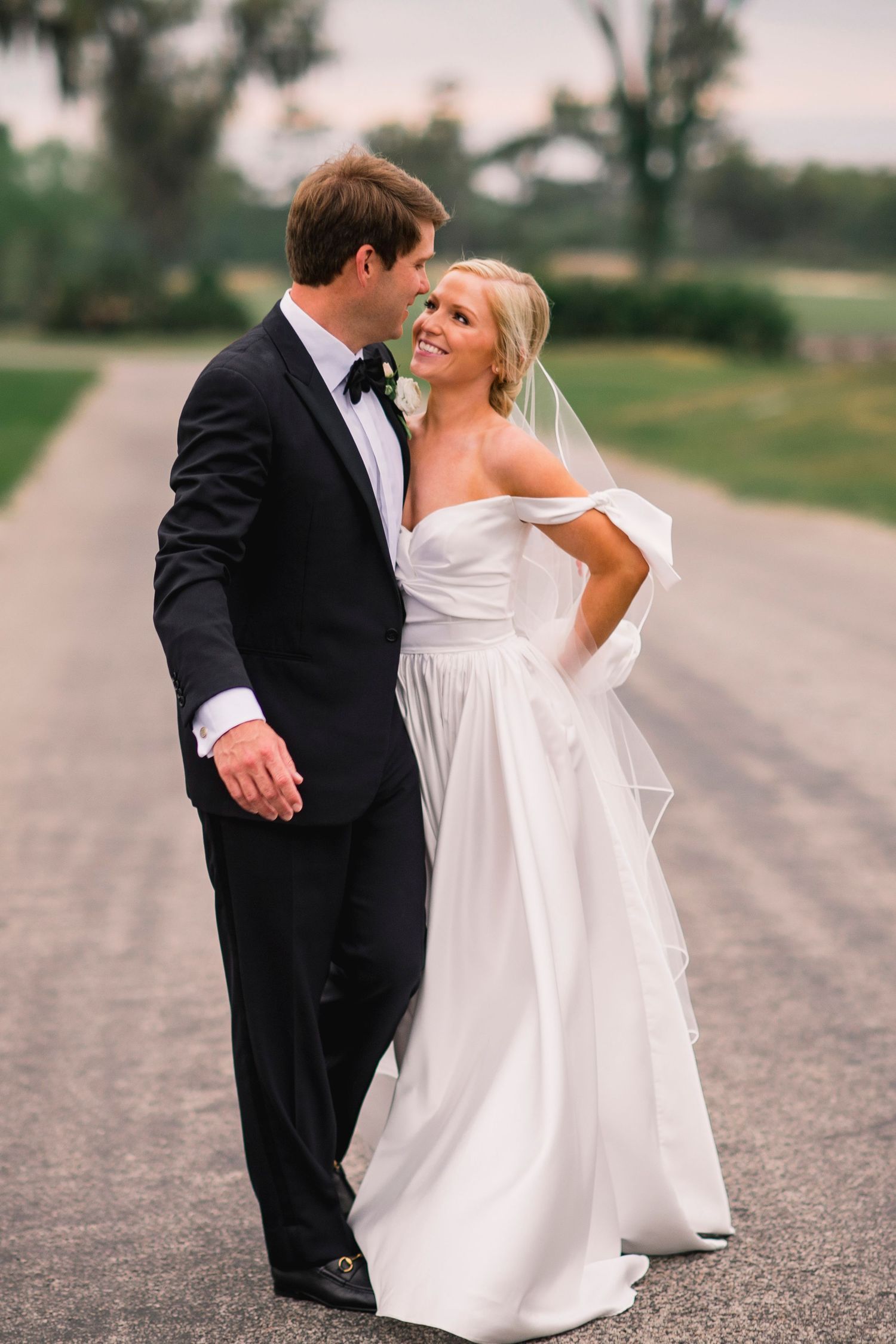 A couple shares intimate moments in formal attire on a quiet road.