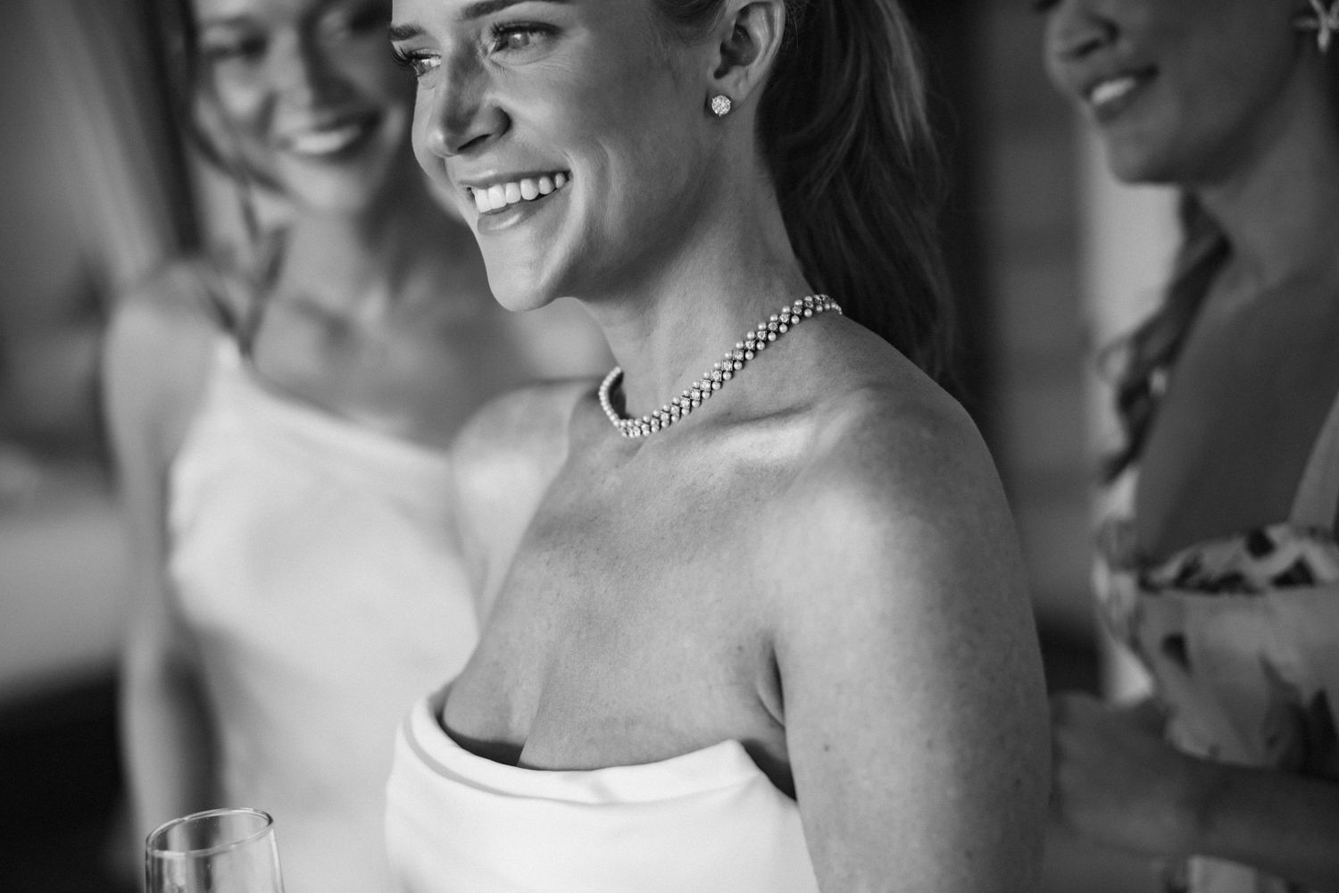 Black and white candid moment during wedding preparations showing elegant jewelry and formal attire.