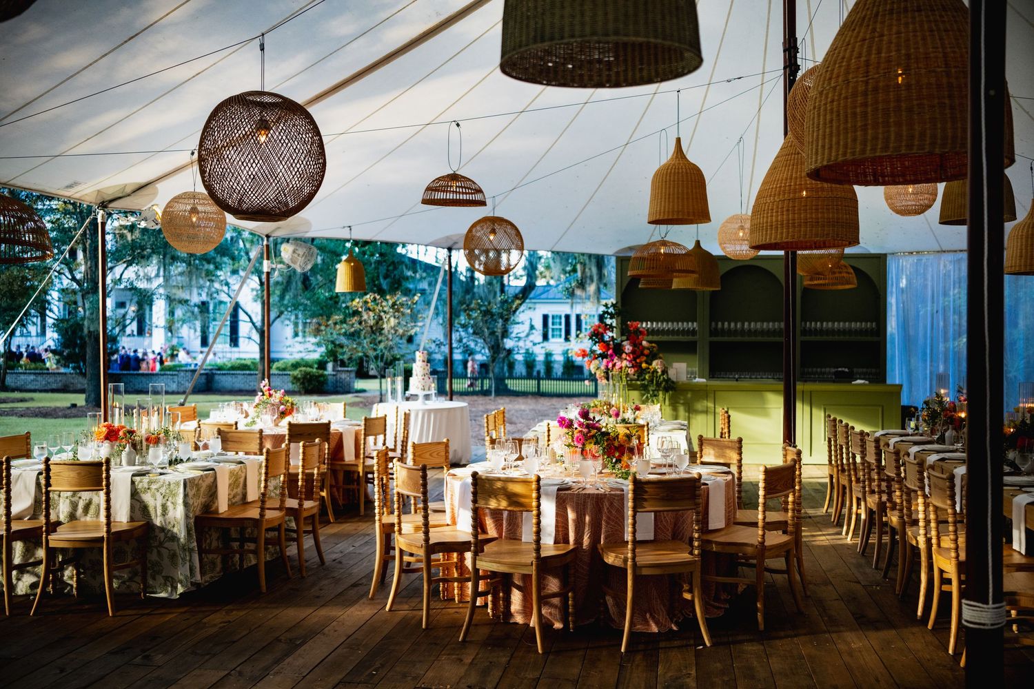 A rustic wedding reception venue with draped fabric ceiling, wooden tables, and pendant lighting creating an elegant atmosphere.
