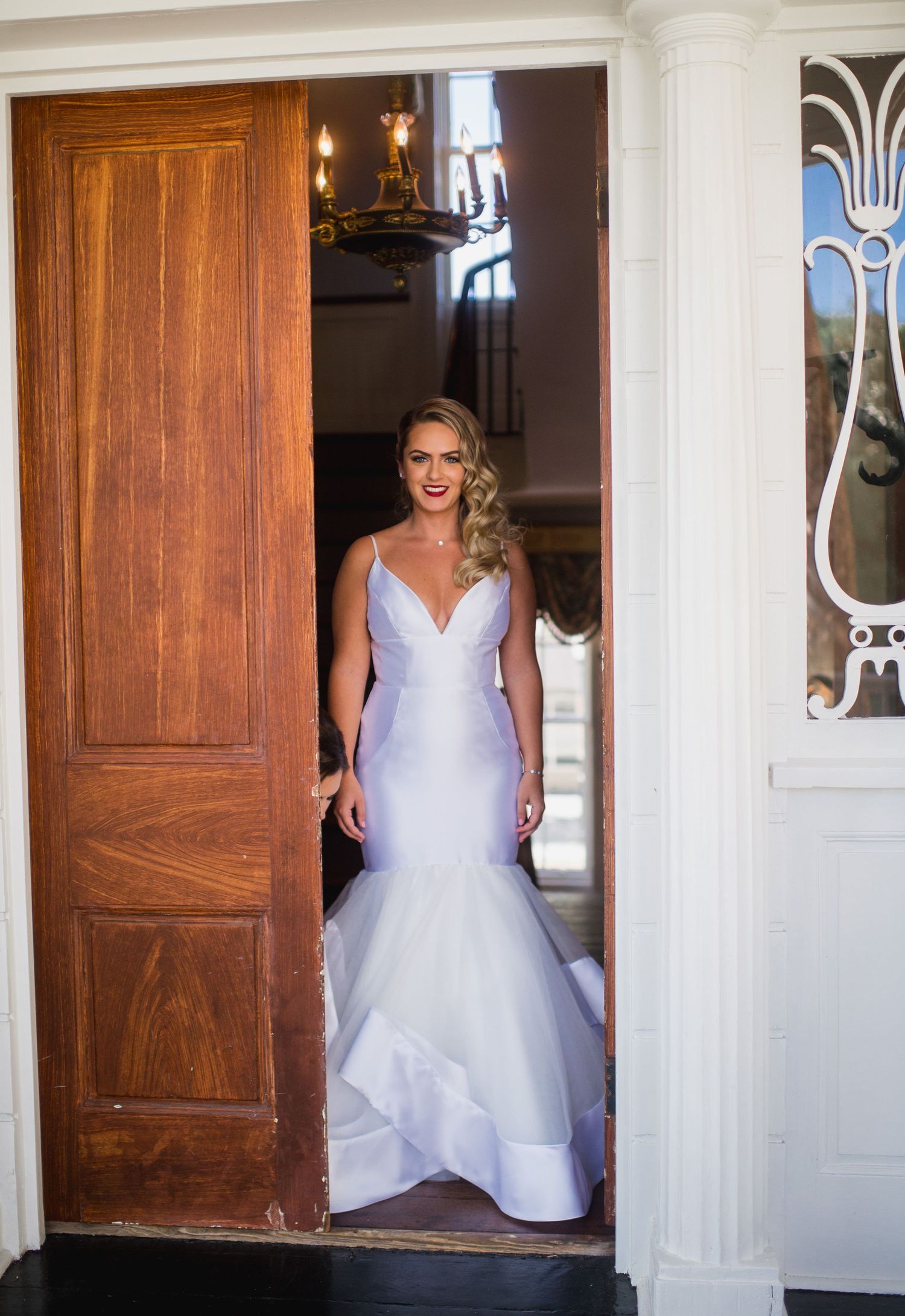 A bride in a white wedding gown enters through a series of wooden doors in a sequence of photos.