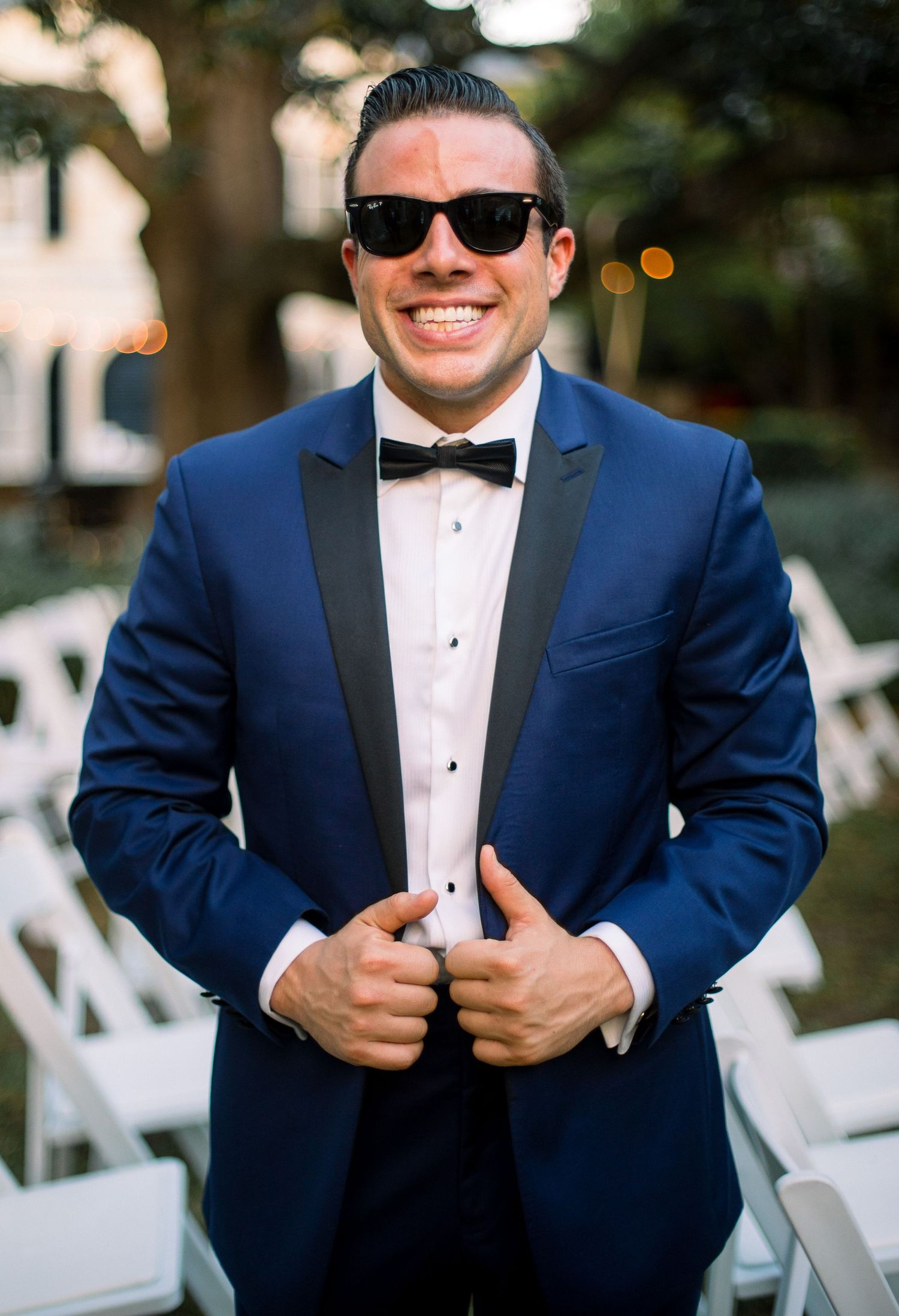 A groom in a navy blue tuxedo and bow tie poses for wedding photos with different expressions and angles.