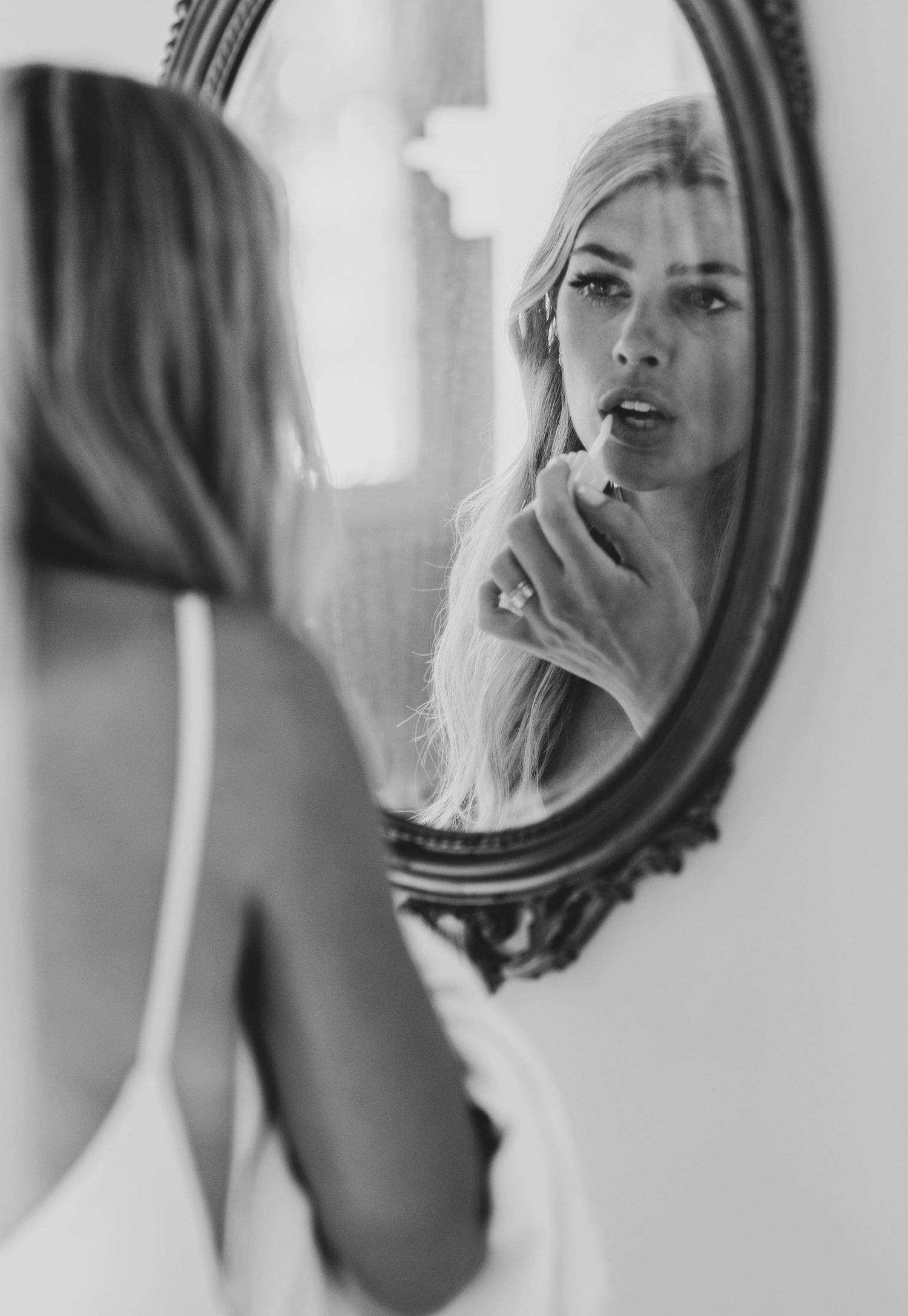 Black and white reflection of a person looking in multiple mirrors creating a repeating pattern effect.