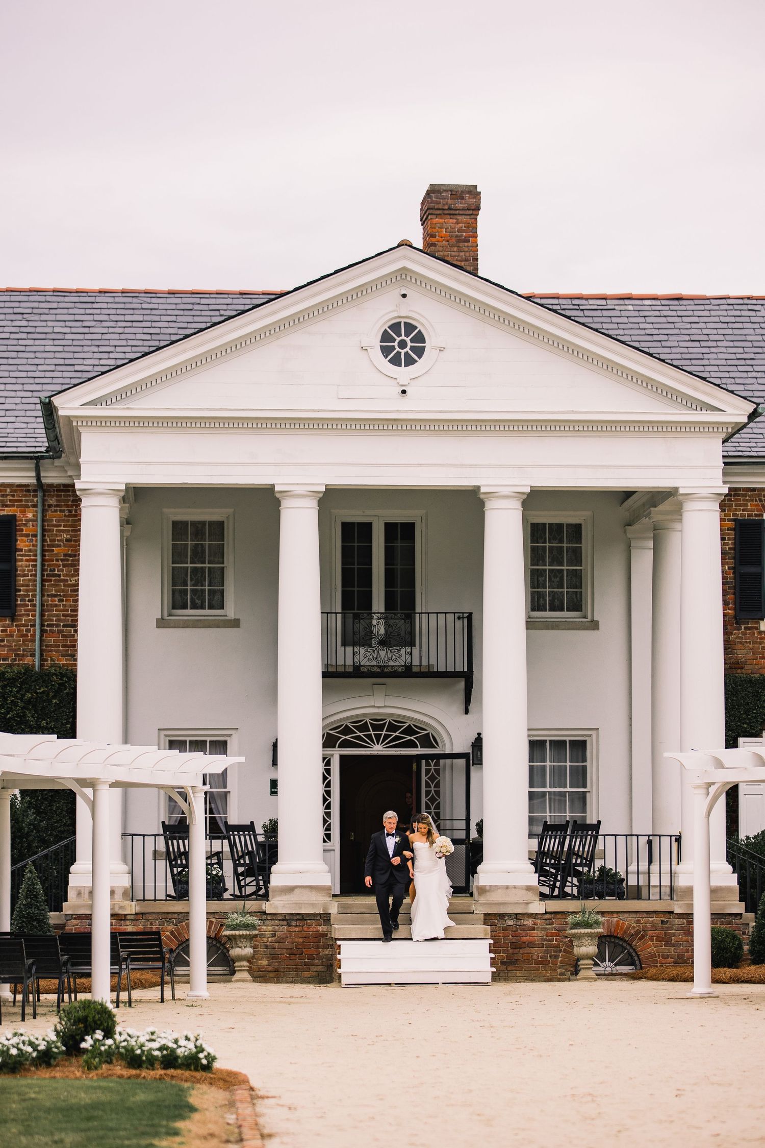White colonial-style mansion with grand pillars and a symmetrical facade features classic Southern architectural details.