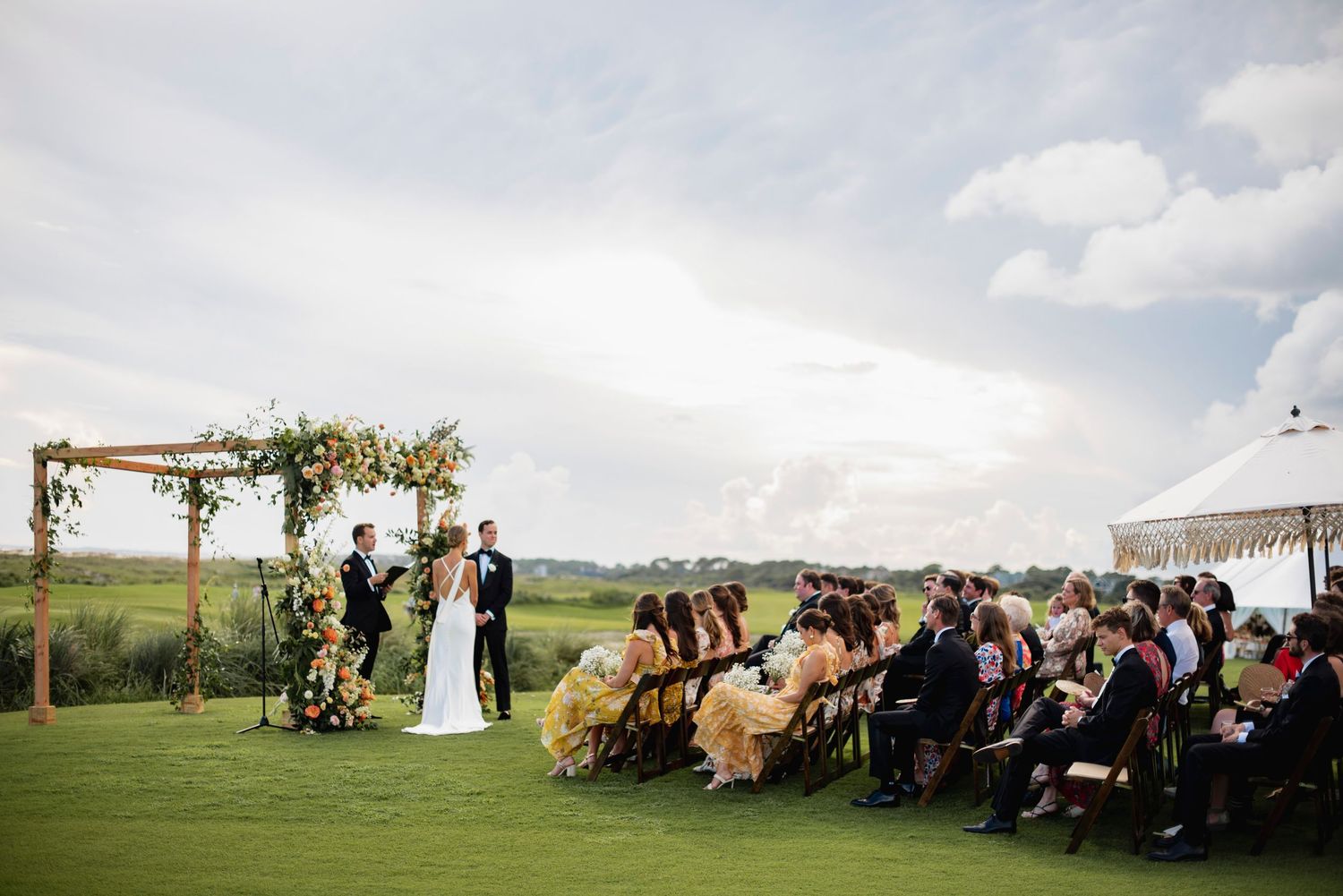 Outdoor wedding ceremony setup with rustic wooden benches and natural decor overlooking rolling countryside hills.