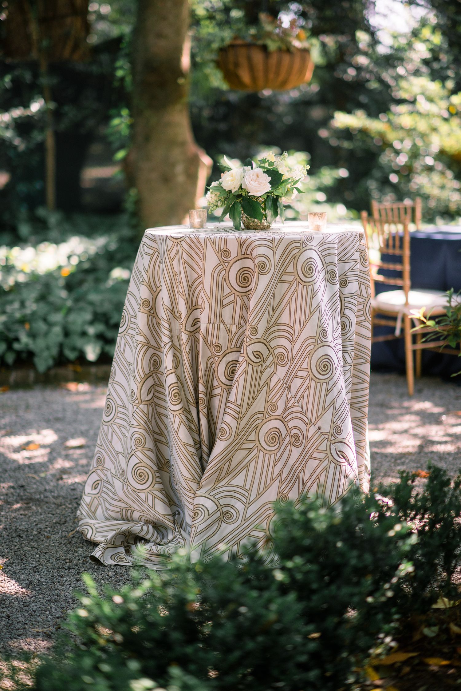 Decorative brown and white patterned tablecloths draped over round tables in an outdoor garden setting.